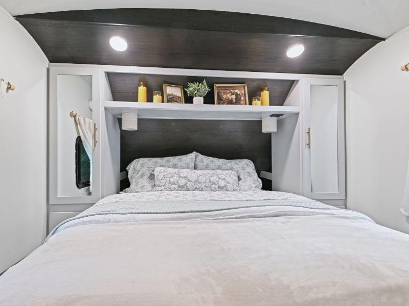 Cozy RV rental bedroom showcasing a bed with patterned bedding, overhead storage, integrated lighting, and decor.. Keystone RV Bullet Premier Ultra 2020