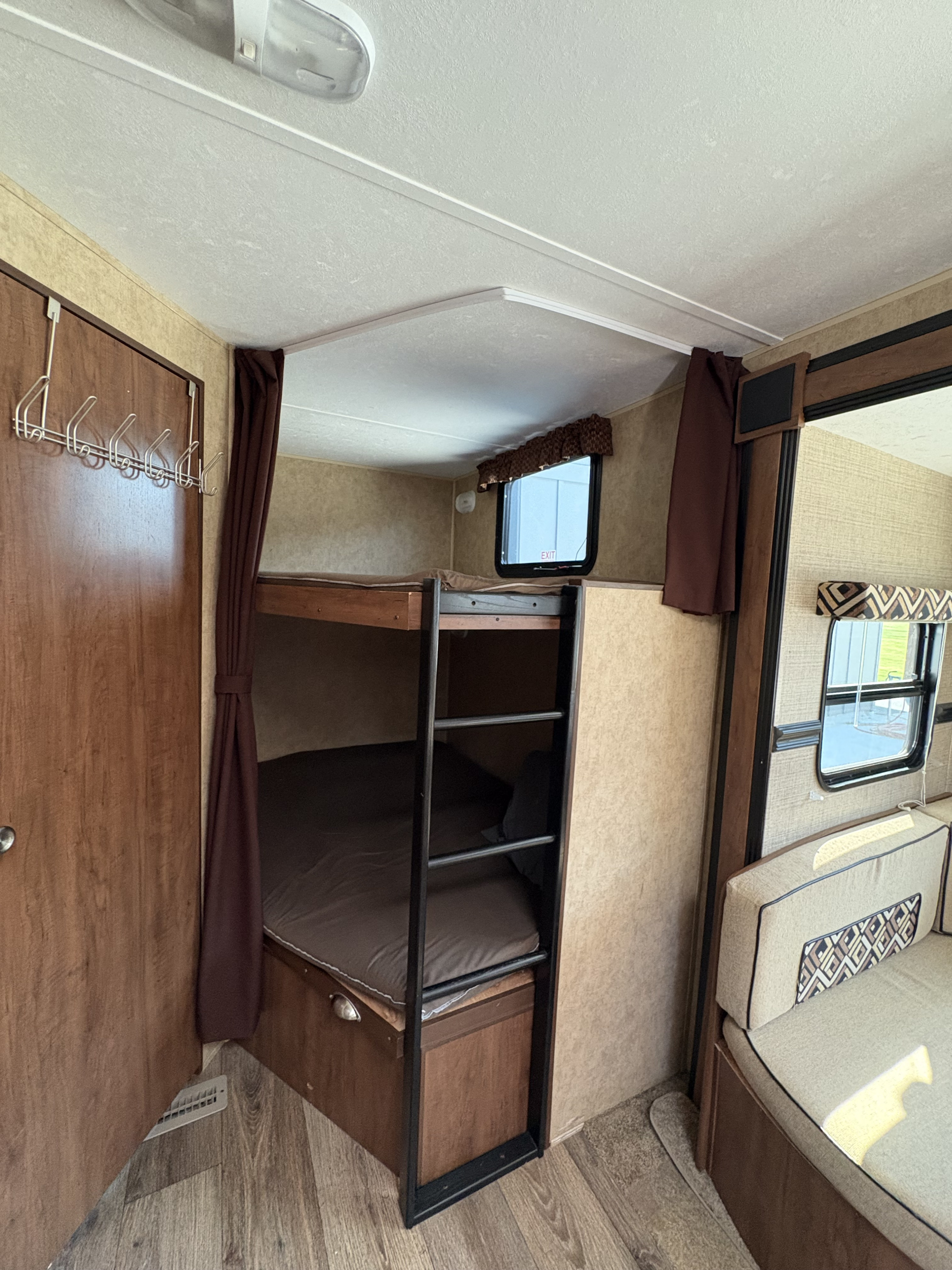 Spacious RV rental interior: bunk beds with ladder, door with hooks, windows, and comfy dinette seating.. Dutchmen Aspen Trail 2810BHS 2014