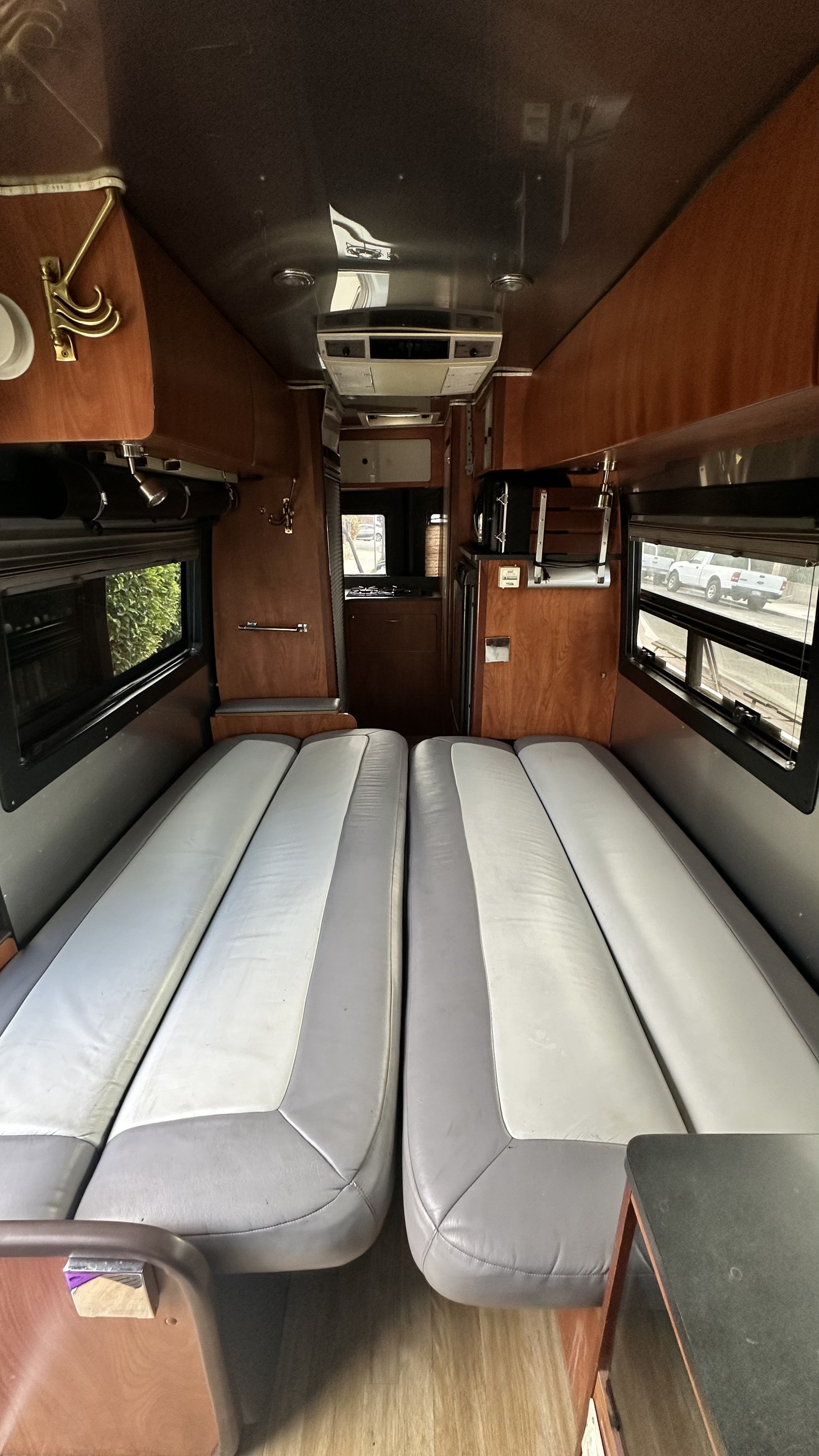 Spacious RV rental interior featuring two long benches for sleeping, a compact kitchen, and side windows.. Airstream Interatate 2003