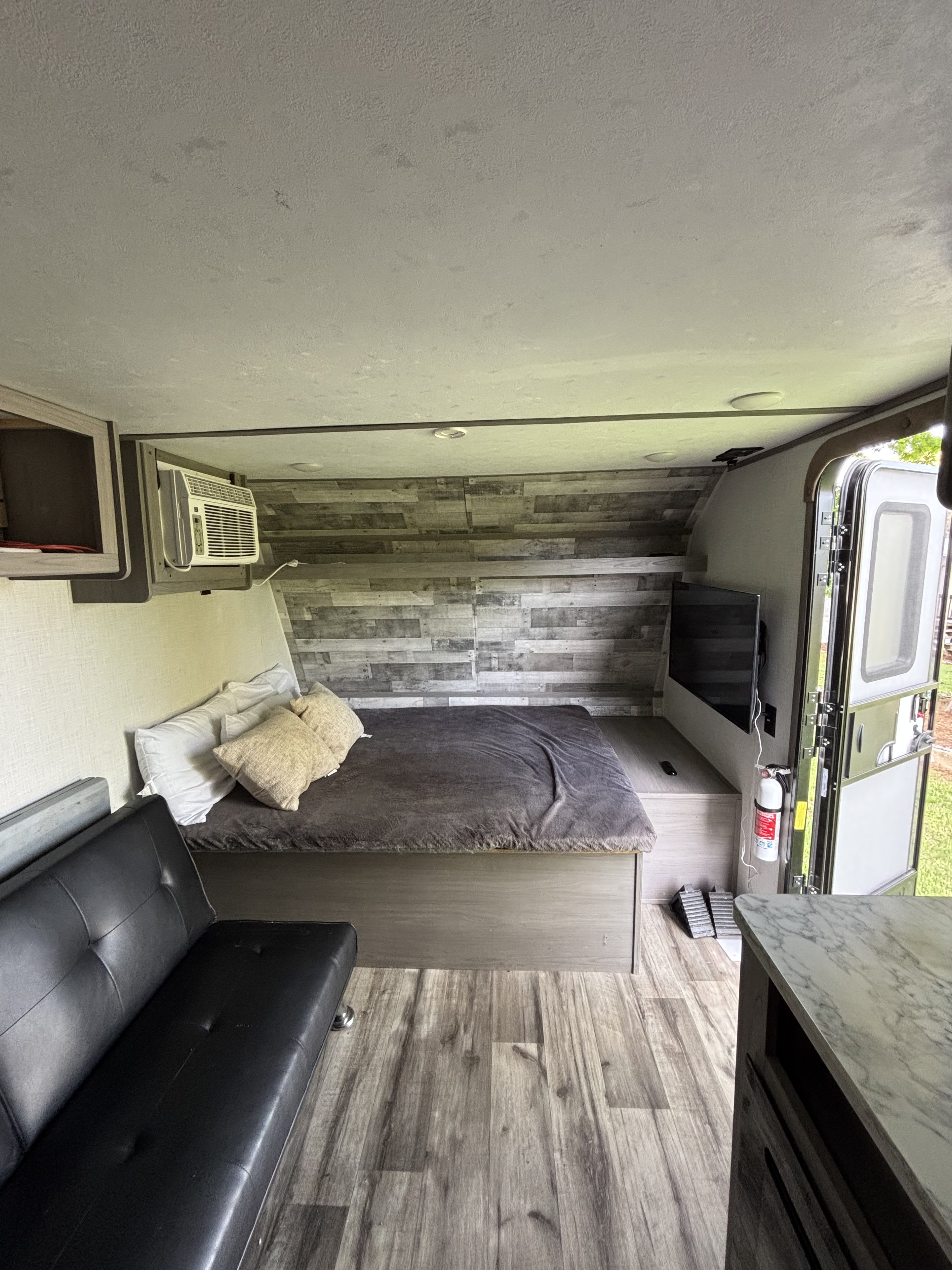 Modern rv rental interior: comfortable bed, sofa, TV, AC, wood-look flooring, and paneled walls create a compact, functional space.. Dutchmen Coleman Lantern LT 2022