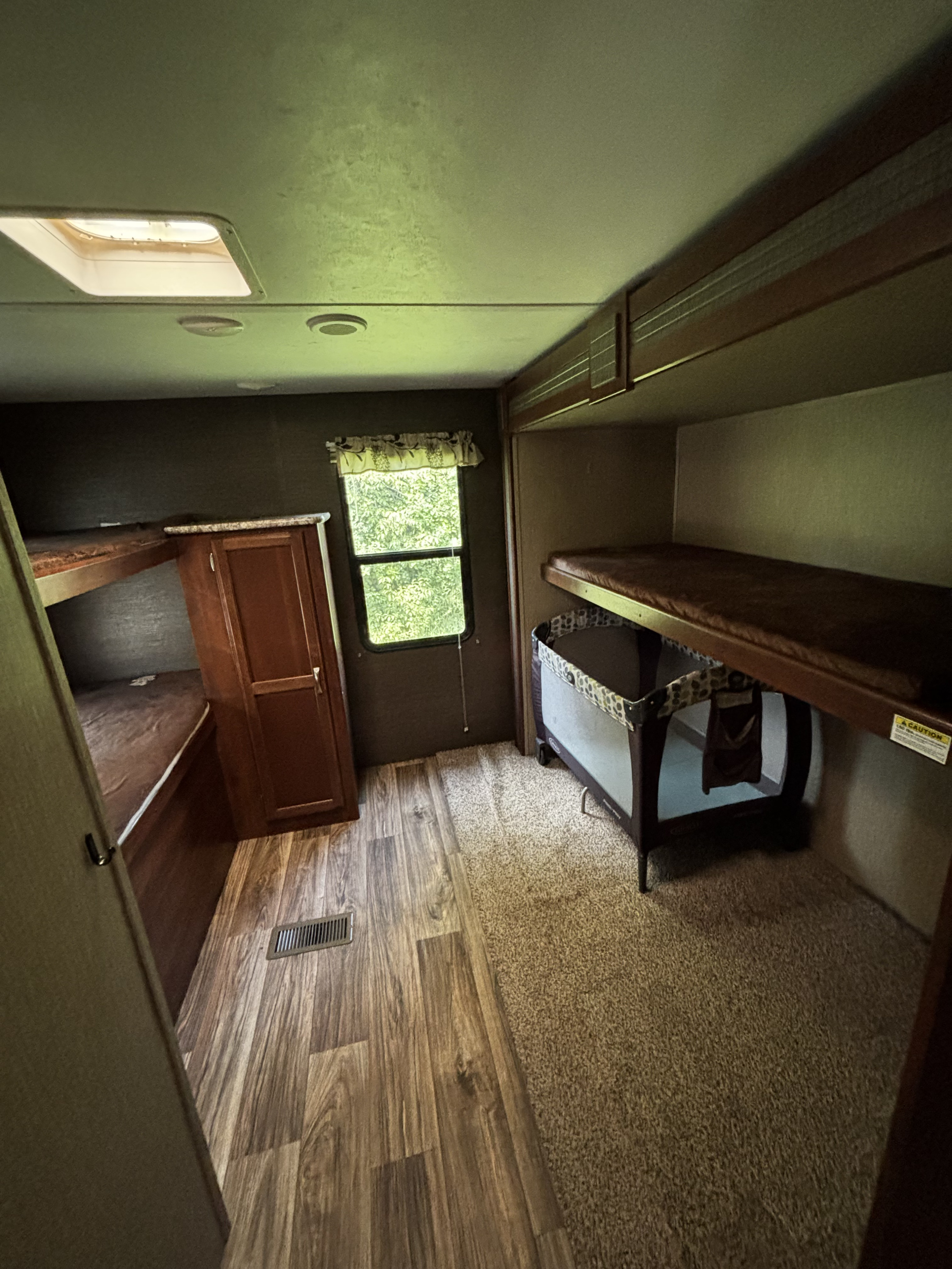 RV rental bunkhouse interior: features multiple beds, a baby playpen, closet, and a bright skylight, perfect for families.. Keystone RV Passport Grand Touring 2016