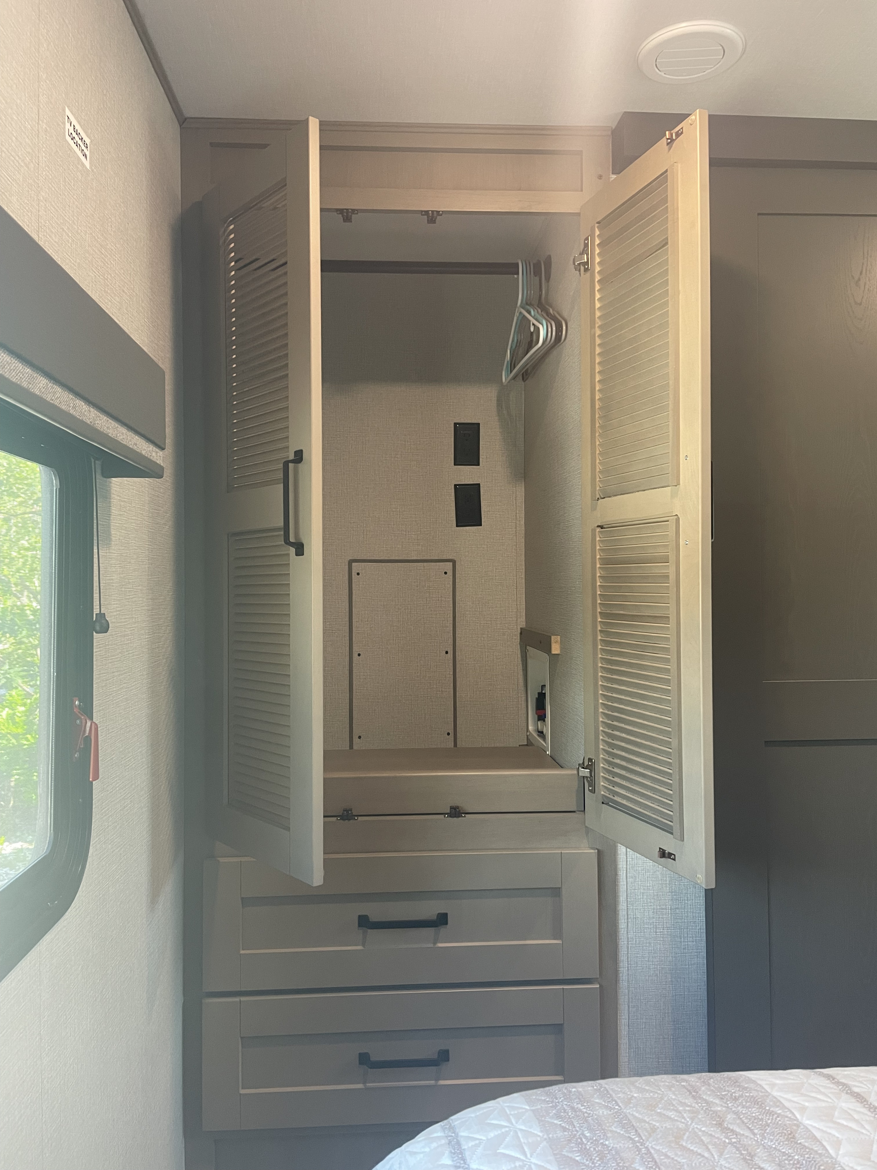 RV rental interior: Open closet with clothes rod, utility hookups for washer/dryer prep, and built-in drawers. Efficient travel storage.. Grand Design Reflection 2024