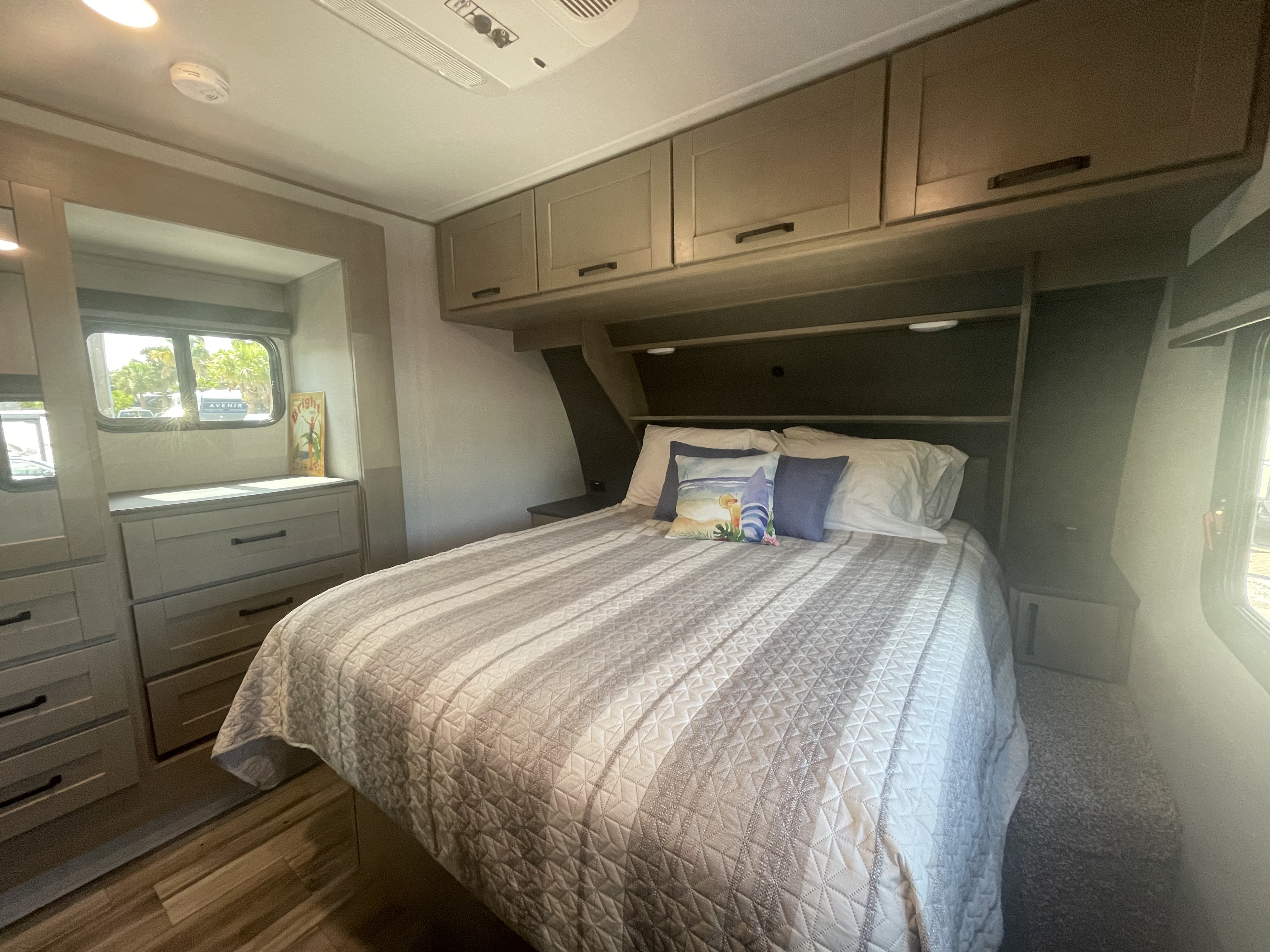 Experience an RV rental: This bright, comfortable bedroom features a striped bed, ample storage, and scenic windows.. Grand Design Reflection 2024