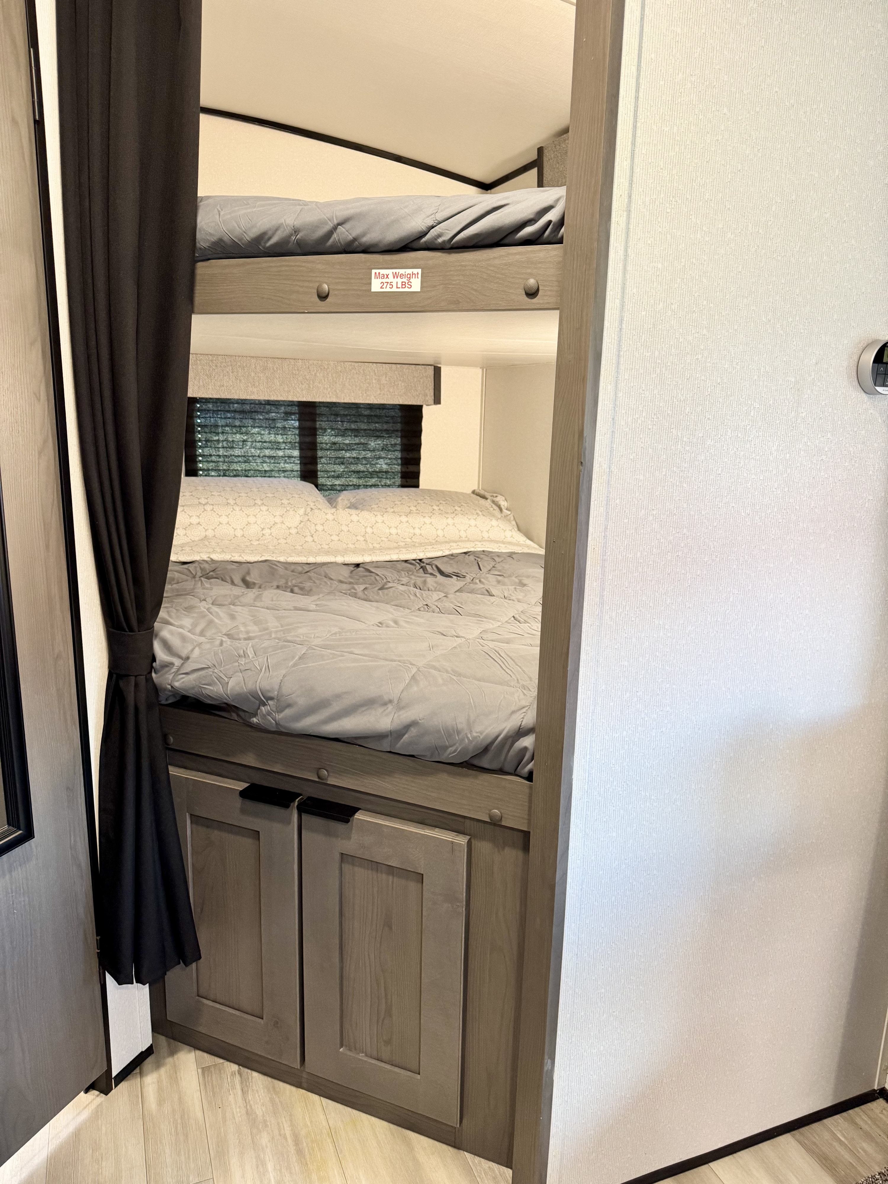 Inside an RV rental: Compact bunk beds with a 275 lbs max weight limit, featuring convenient storage cabinets.. Cruiser RV MPG Ultra Lite 2022