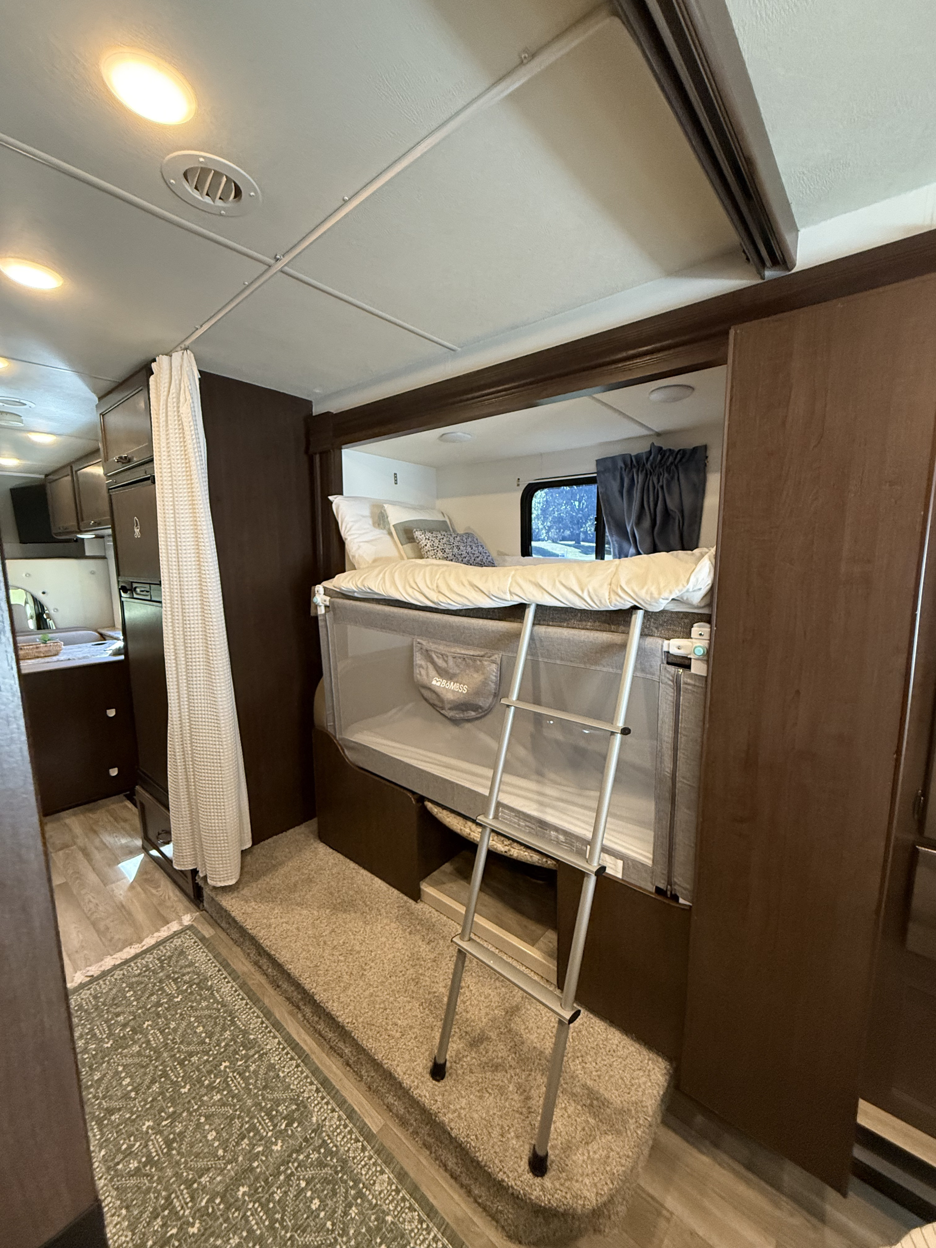 Cozy RV rental interior featuring family-friendly bunk beds with a baby crib below and a functional kitchen area.. Thor Freedom Elite 2018