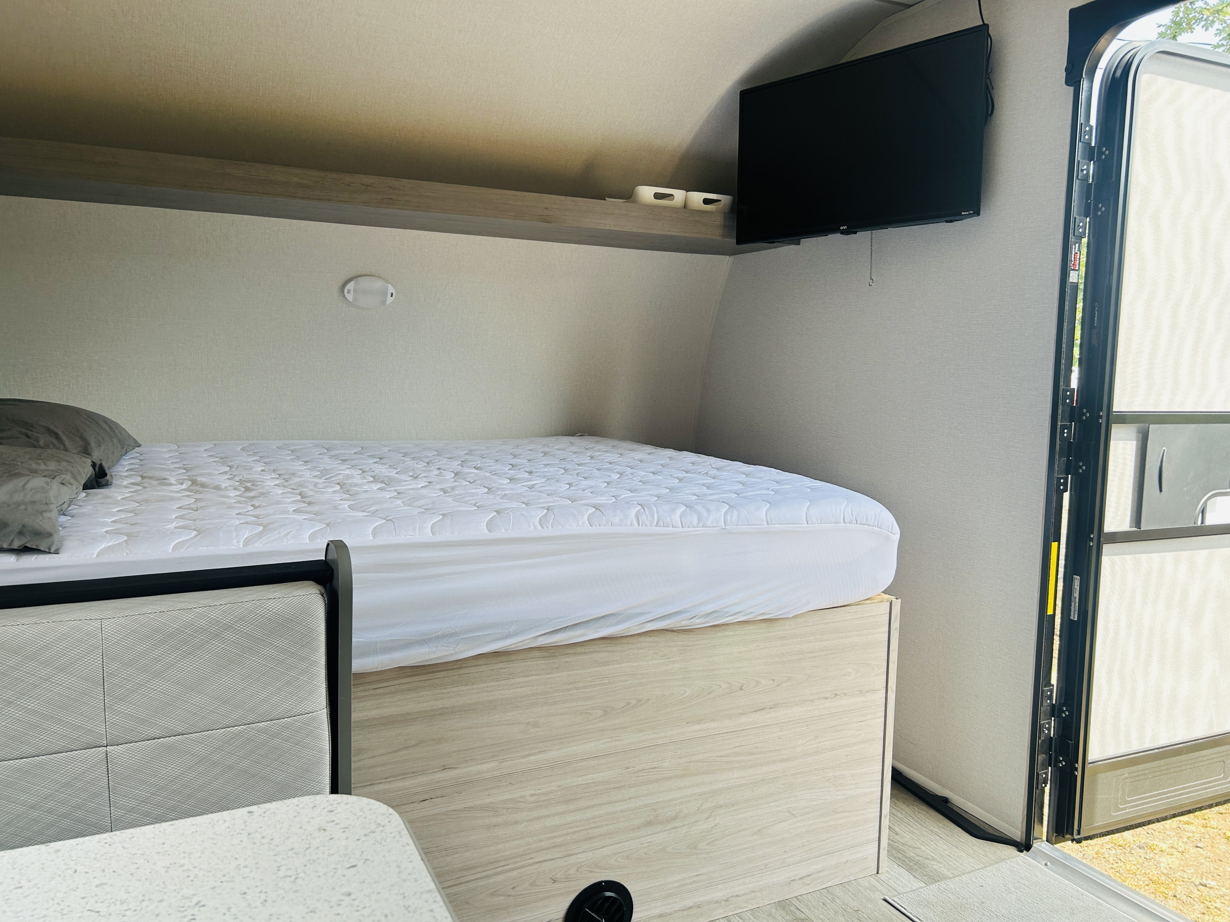 RV rental interior: a cozy sleeping area with a bed, TV, and open door, offering a glimpse of the outdoors.. Heartland Mallard 17BHL 2025