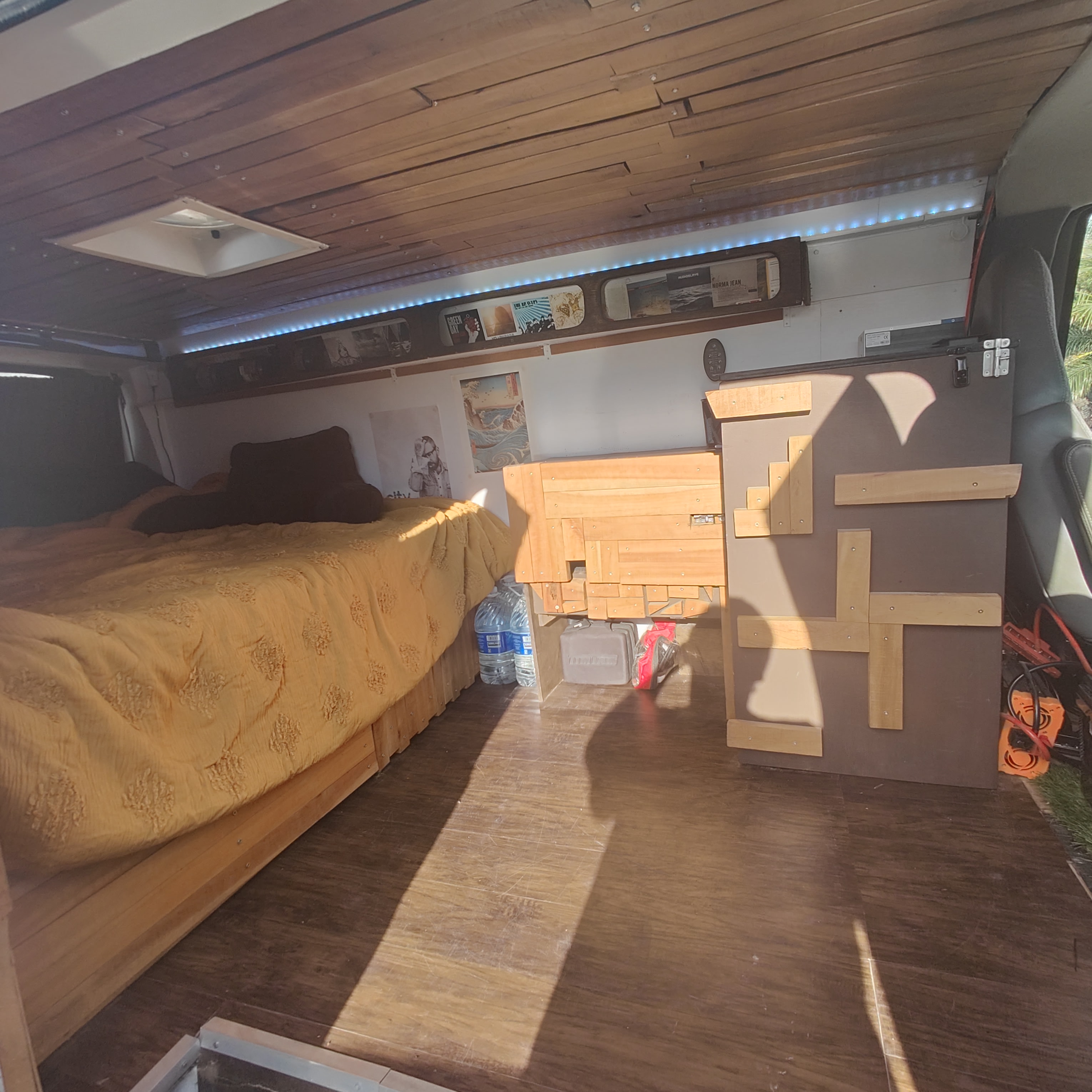 Inside a custom RV rental: cozy bed, wood-paneled ceiling with LED lights, and smart storage, perfect for van life travel.. Chevrolet CHEVY EXPRESS 1500 2004