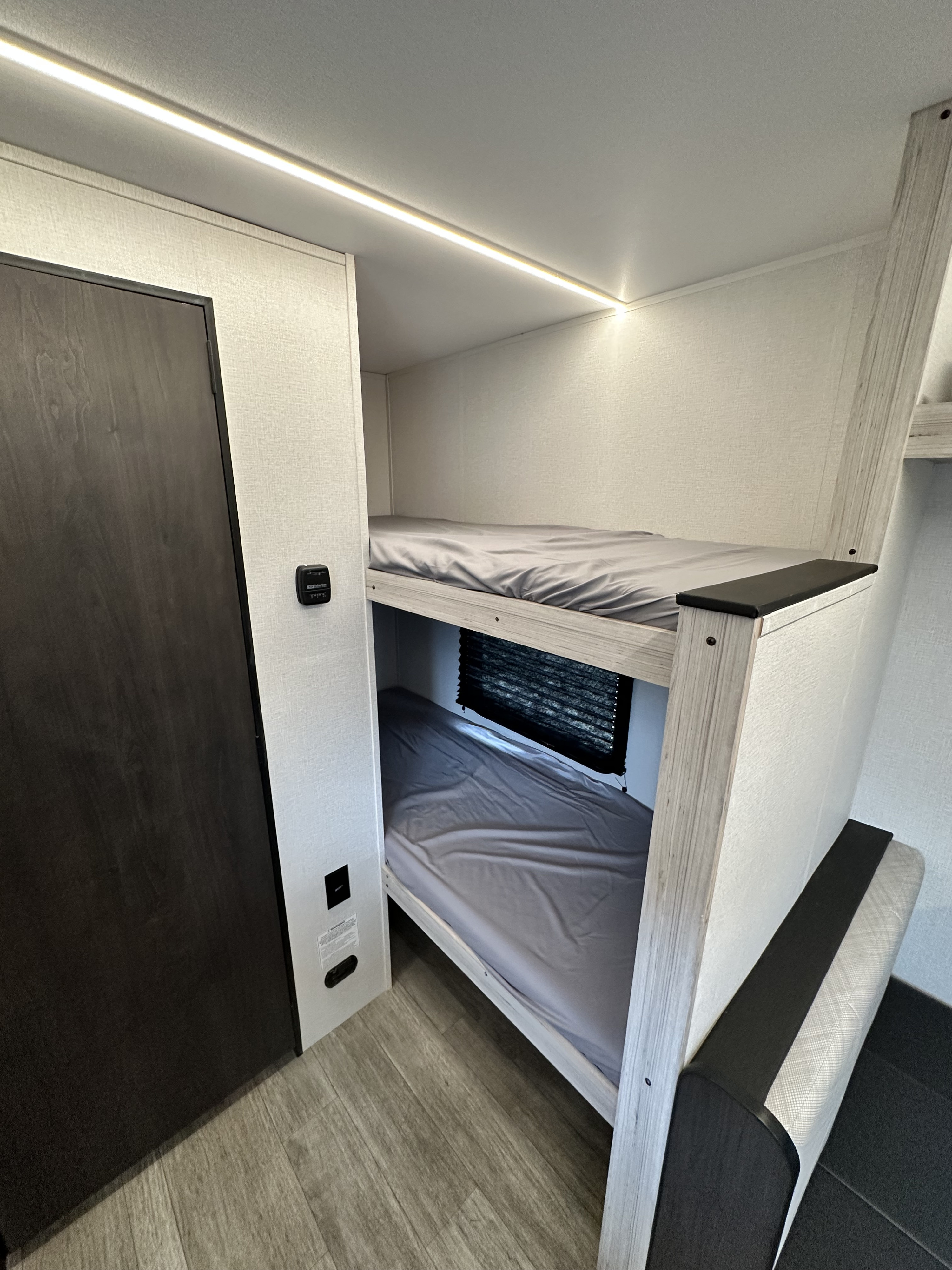 RV rental bunk beds: a clean, modern interior with top bunk LED lighting, a lower bunk window, and wood-look flooring.. Heartland Mallard 2025