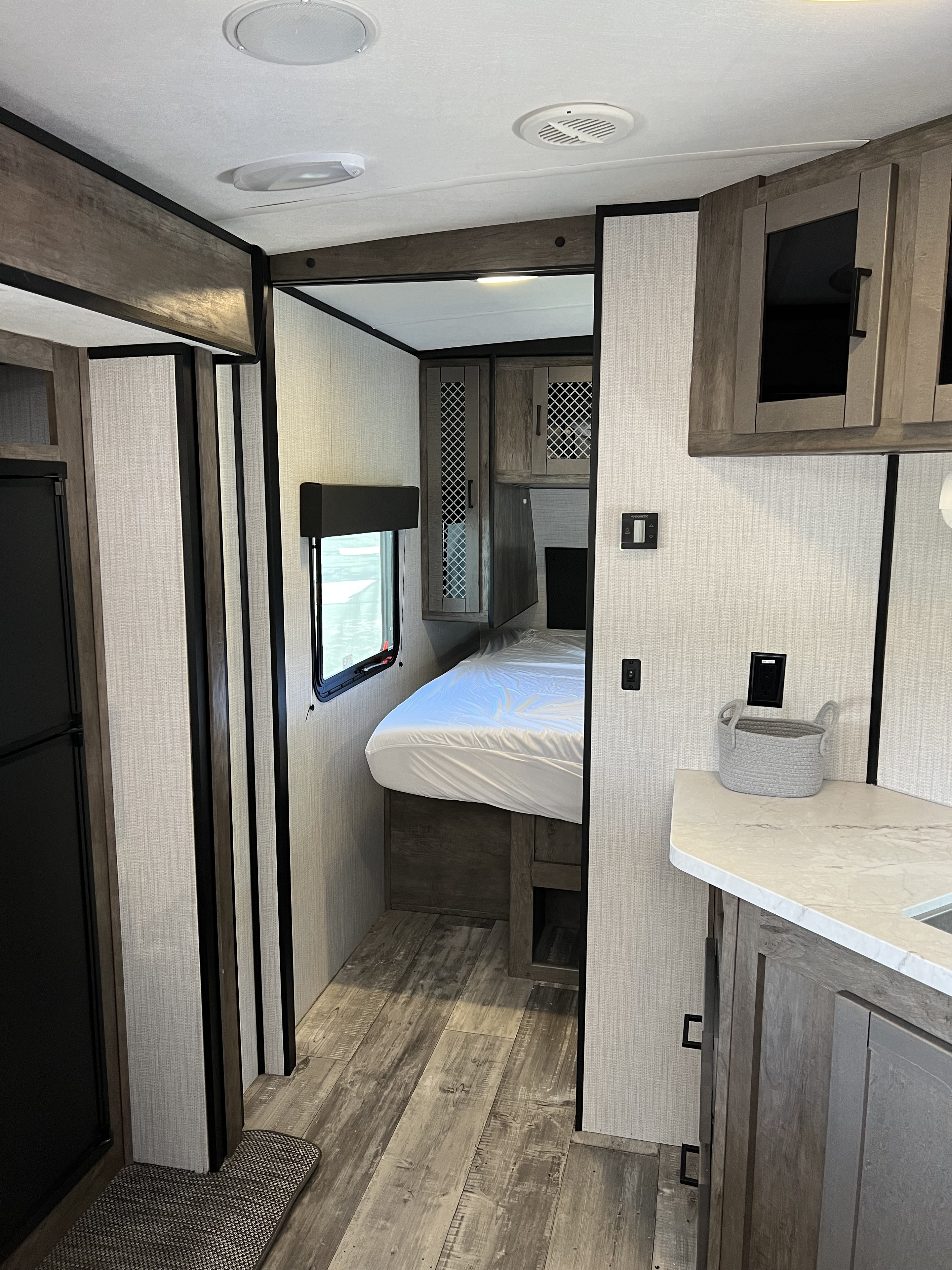 RV rental interior: A compact bedroom with a bed & window, beside a partial kitchen with counter & sink.. Heartland RVs North Trail 2021