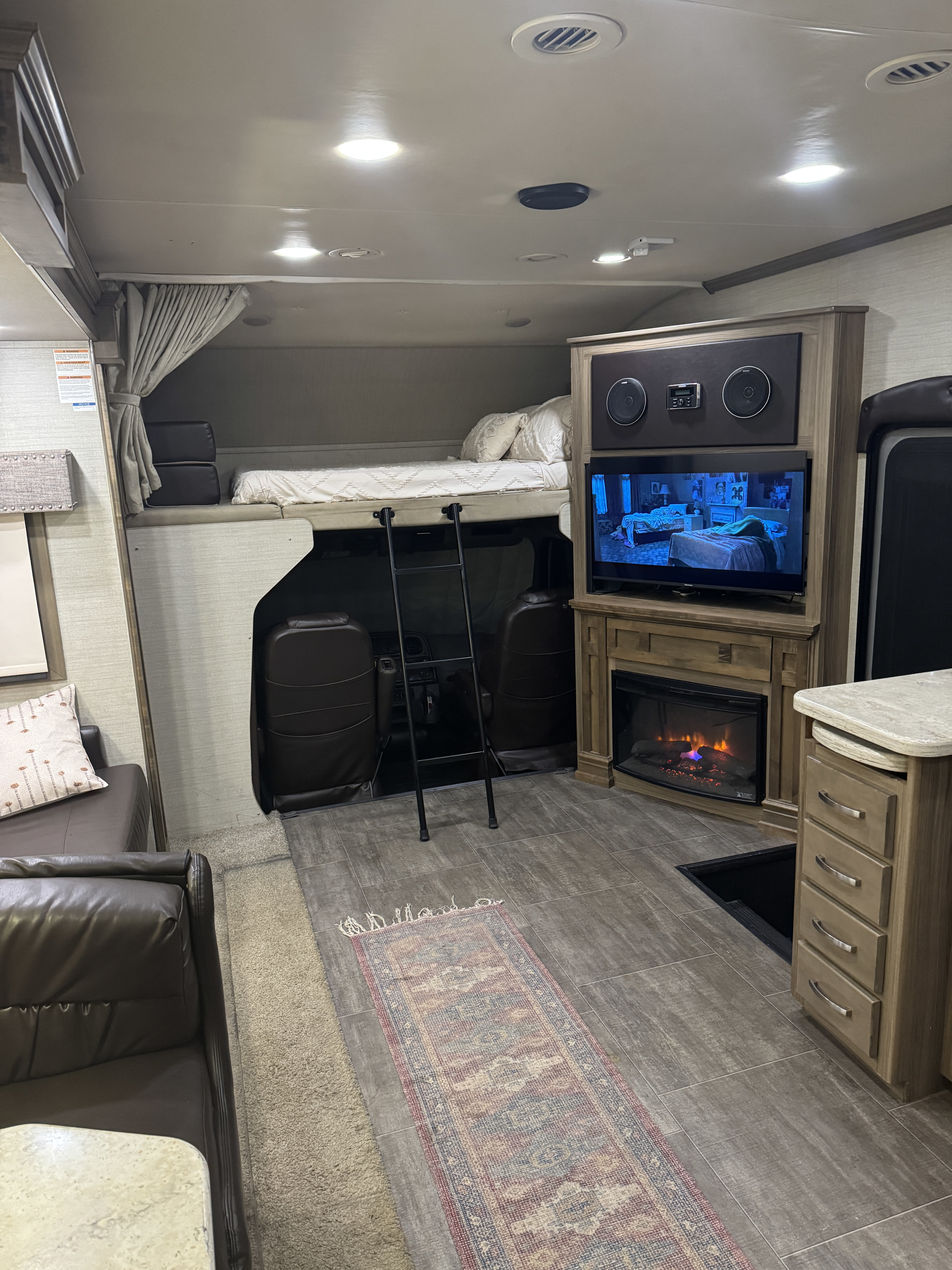 Cozy RV rental interior with a bed, TV, and fireplace. This spacious motorhome offers comfort for travel.. Jayco Seneca 2018
