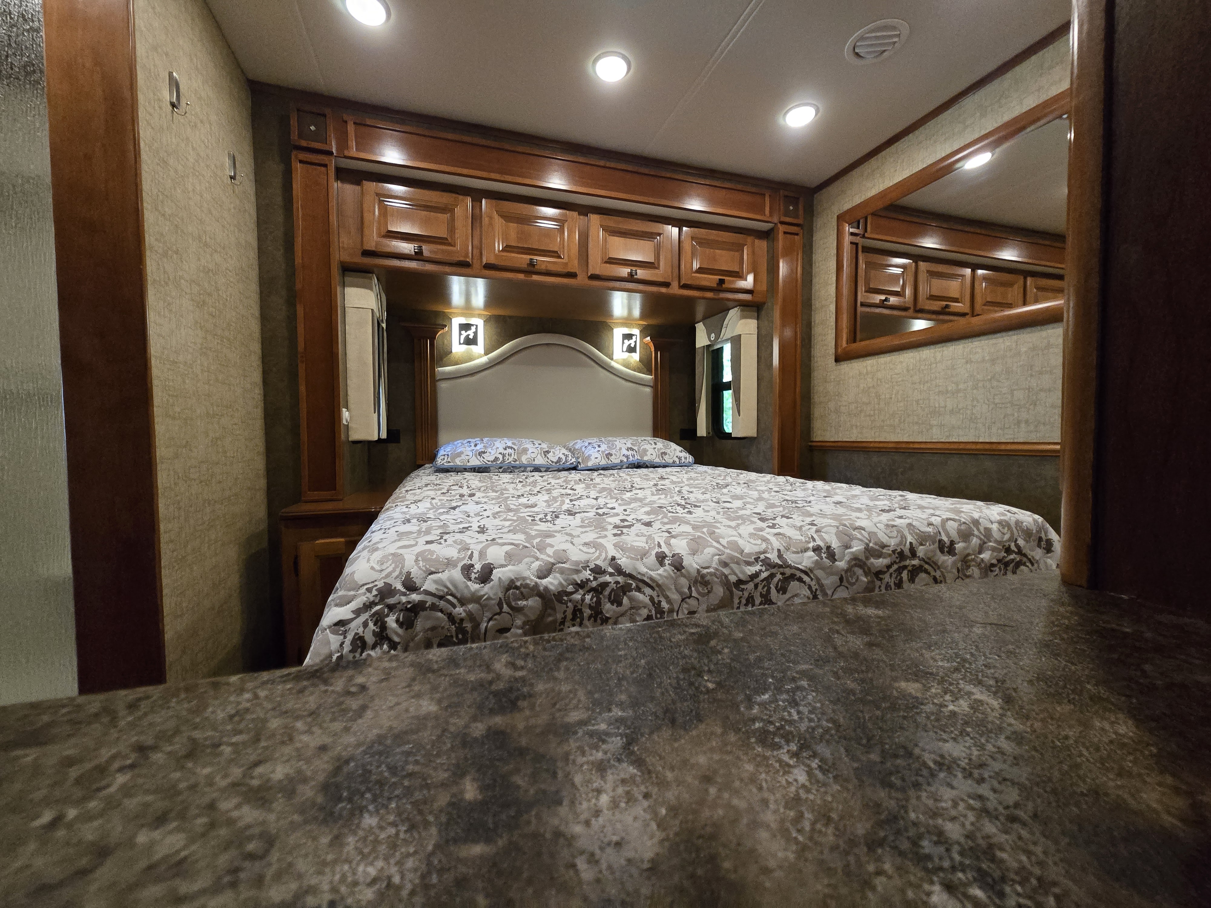Comfortable RV rental bedroom featuring a spacious bed, overhead storage, ambient lighting, and warm wood accents.. Allegro Allegro Motorhome 2014