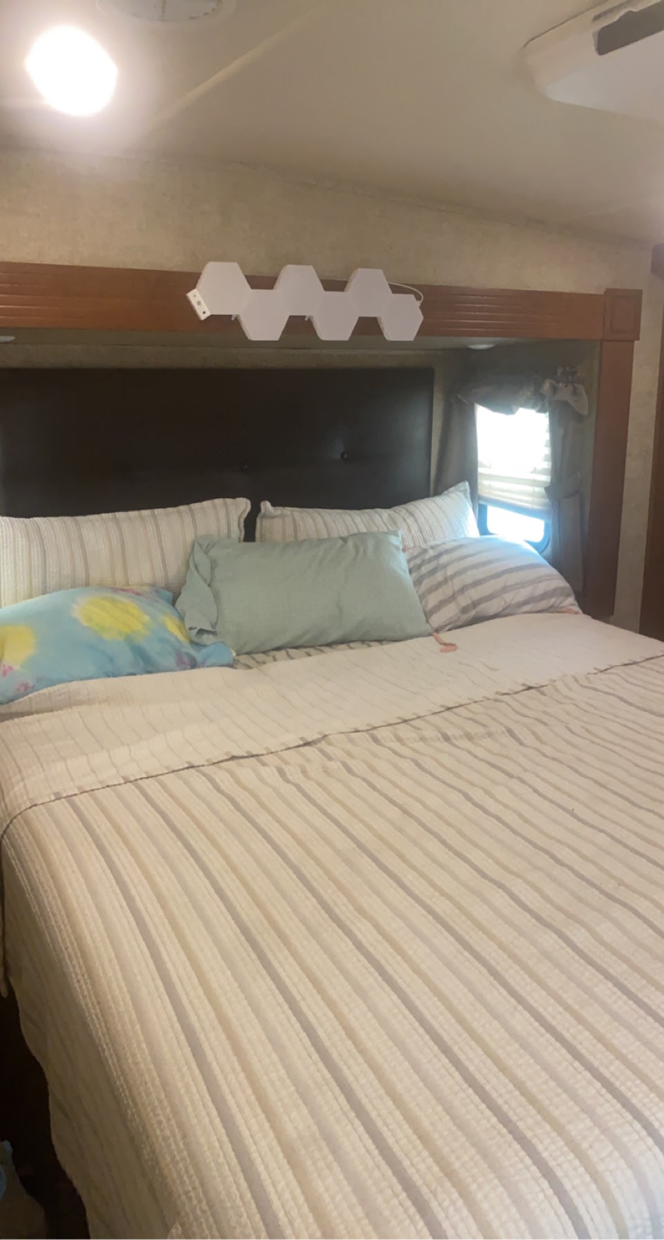 Cozy RV rental bedroom featuring a comfortable bed, pillows, headboard, and unique hexagonal lights. Ideal for travel.. Forest River Sierra 2016
