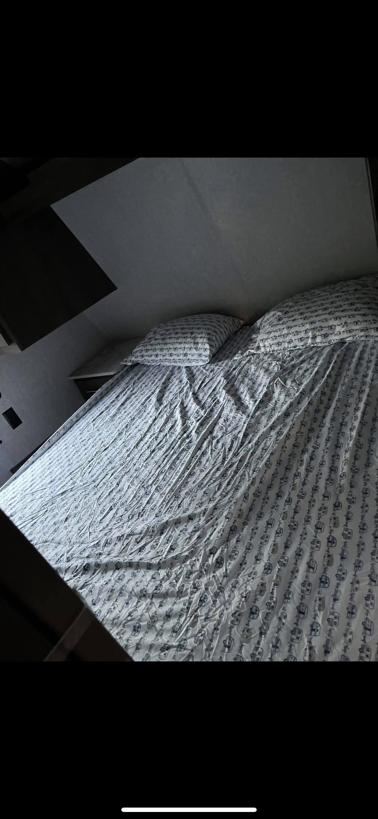 Comfortable RV rental bed, prepared with pillows and sheets patterned with small campers.. Dutchmen Coleman Lantern 2021