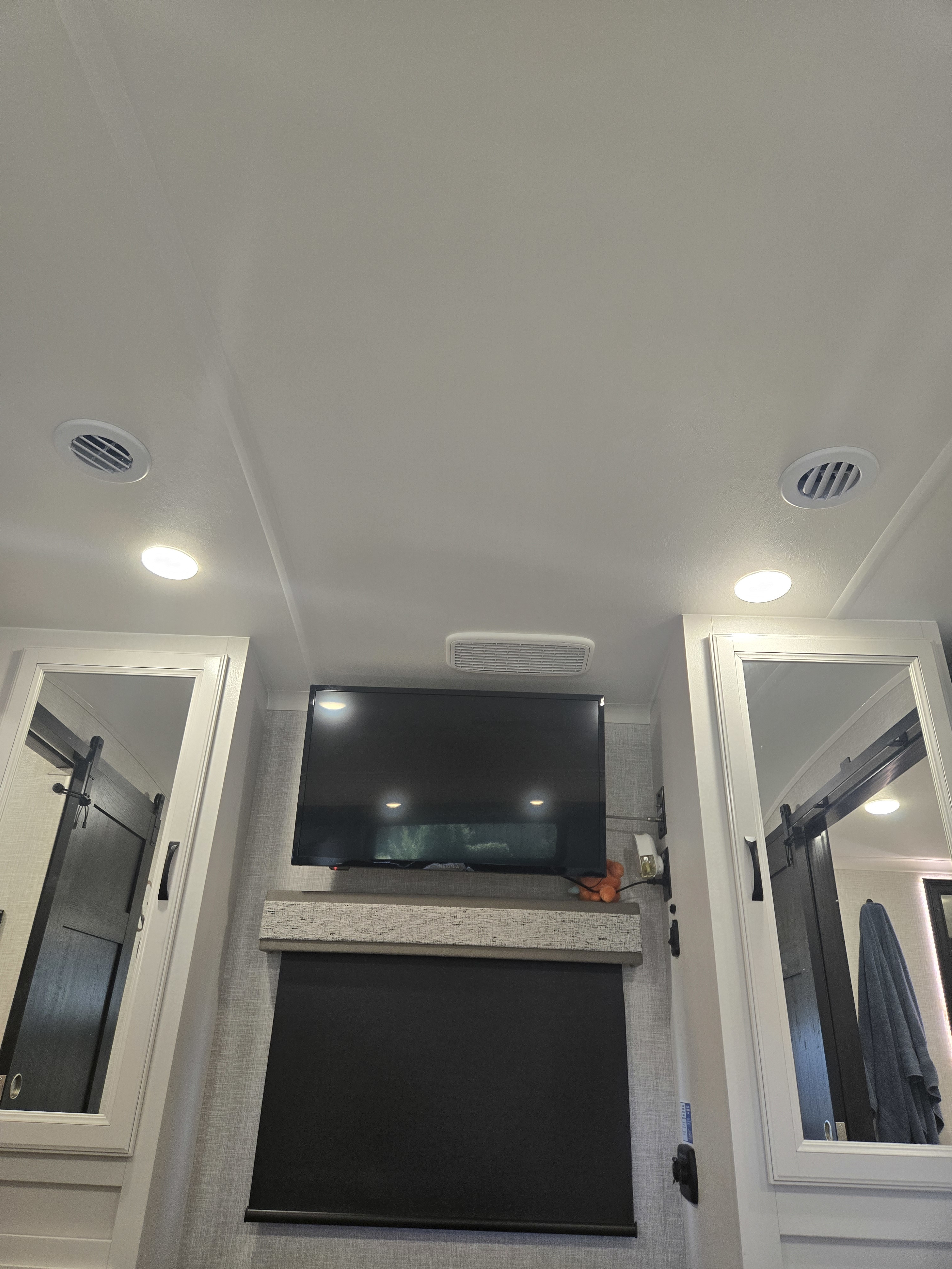 Inside a spacious RV rental: ceiling with AC vents & lights, TV, roller blind, & mirrored wardrobes.. Jayco North Point 2024
