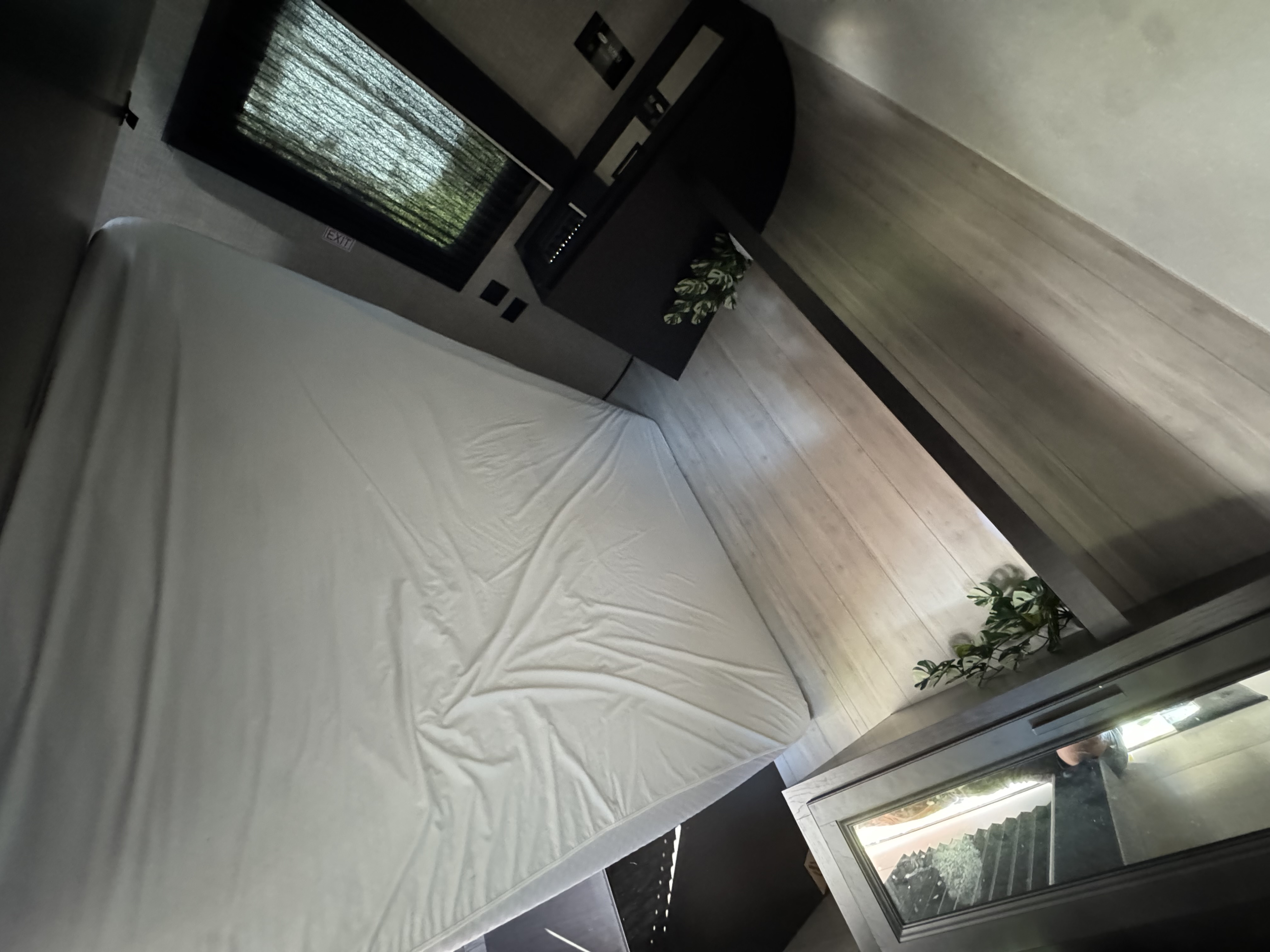 Cozy RV rental bedroom featuring a large white bed, window, and dark wood-toned cabinetry. Ideal for travel.. Jayco Jay Flight SLX 2022