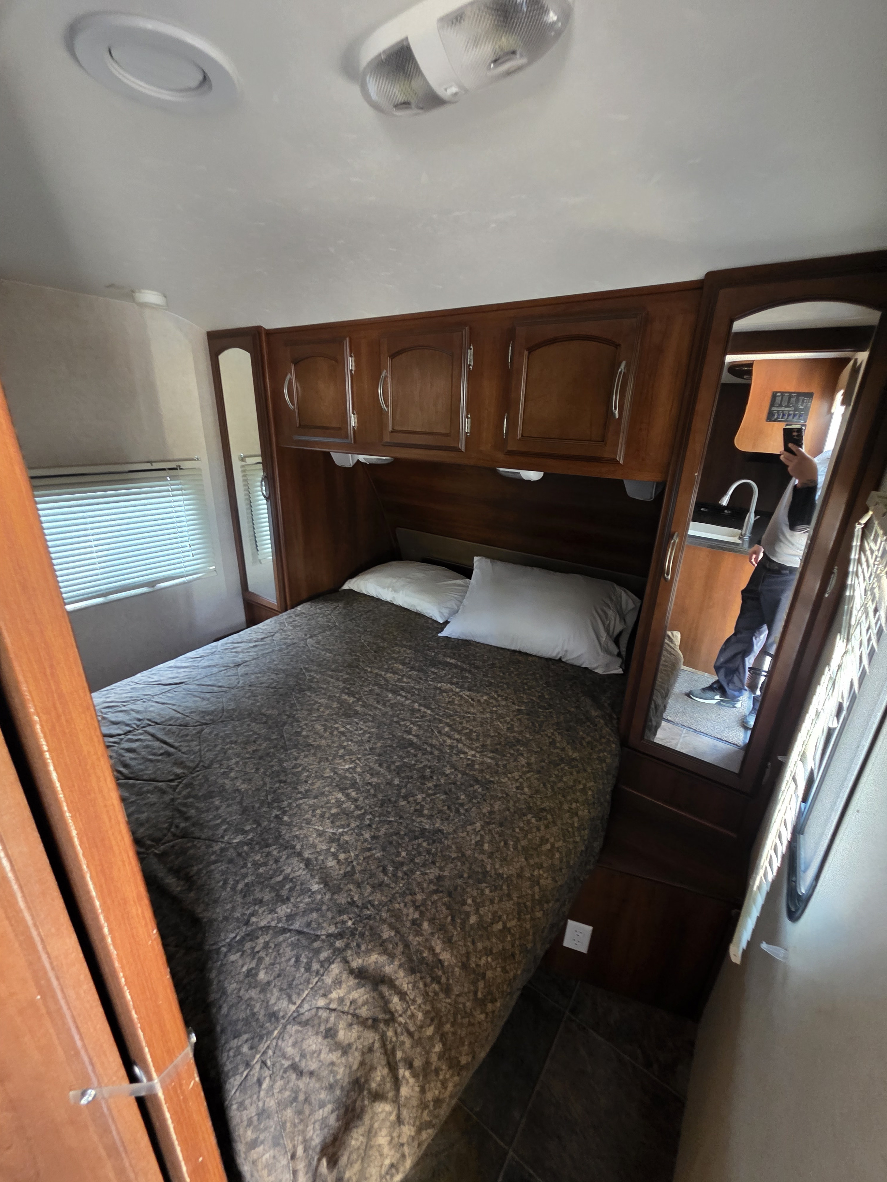 Cozy RV rental bedroom with a comfortable bed, overhead cabinets, and a mirrored wardrobe, perfect for your travels.. Forest River Coachmen Freedom Express 2012