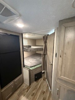 This RV rental interior features bunk beds, a refrigerator, and a door leading to a bathroom or storage. Perfect for family travel.. Forest River Palomino Puma XLE 2020