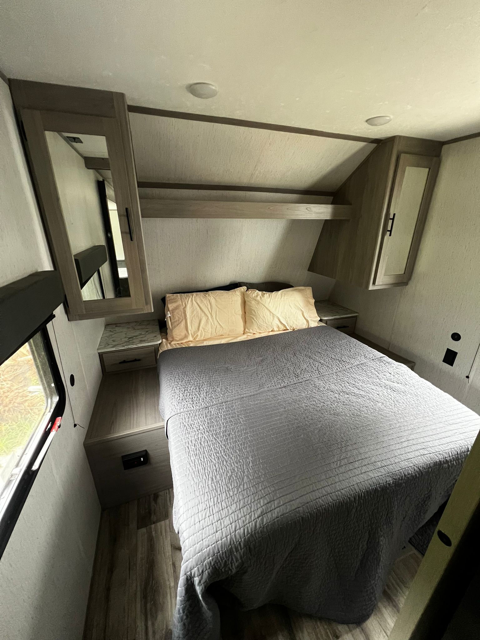 RV rental bedroom with a cozy bed, overhead storage, and window, offering a compact, functional sleeping space.. Dutchmen Coleman Lantern 2022