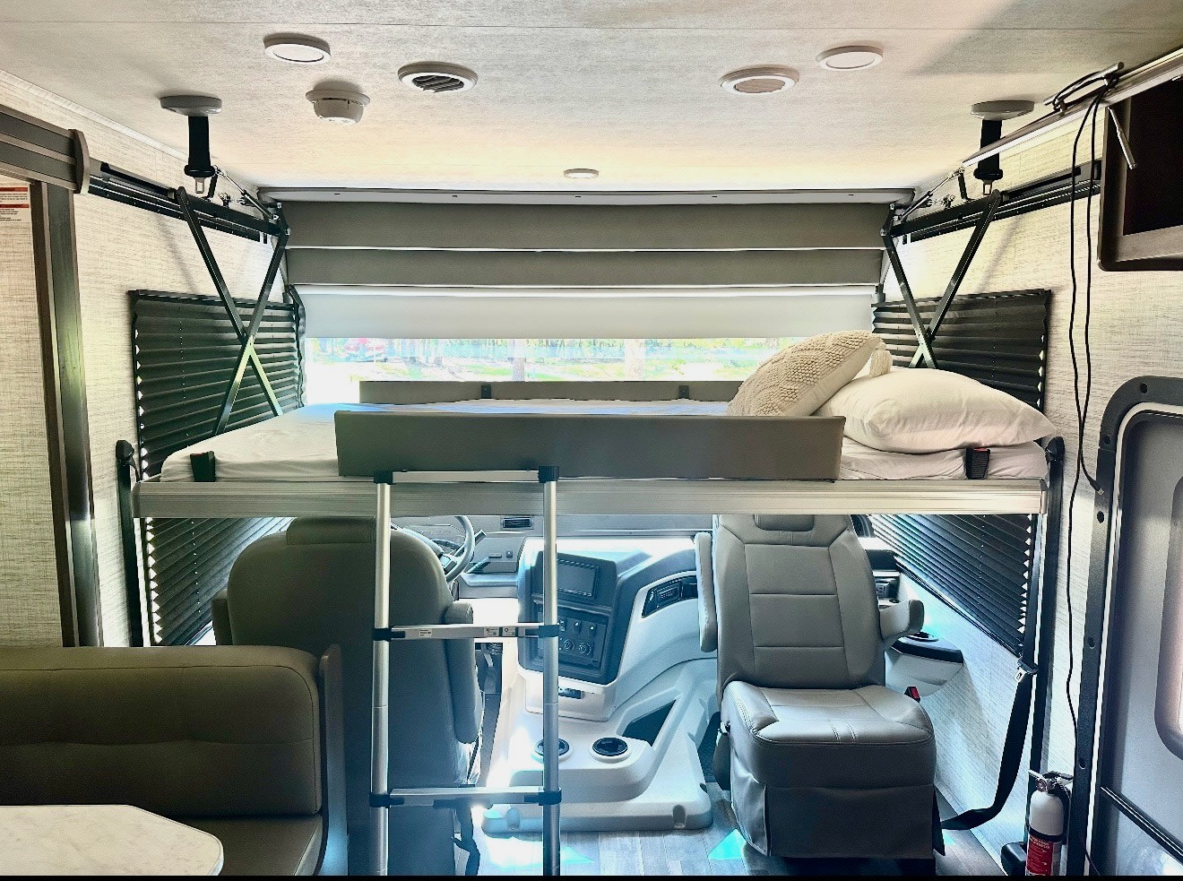 RV rental's innovative interior features a dropped bunk bed over the cockpit seats, complete with ladder and bedding.. Entegra Coach Vison 27ASE 2025