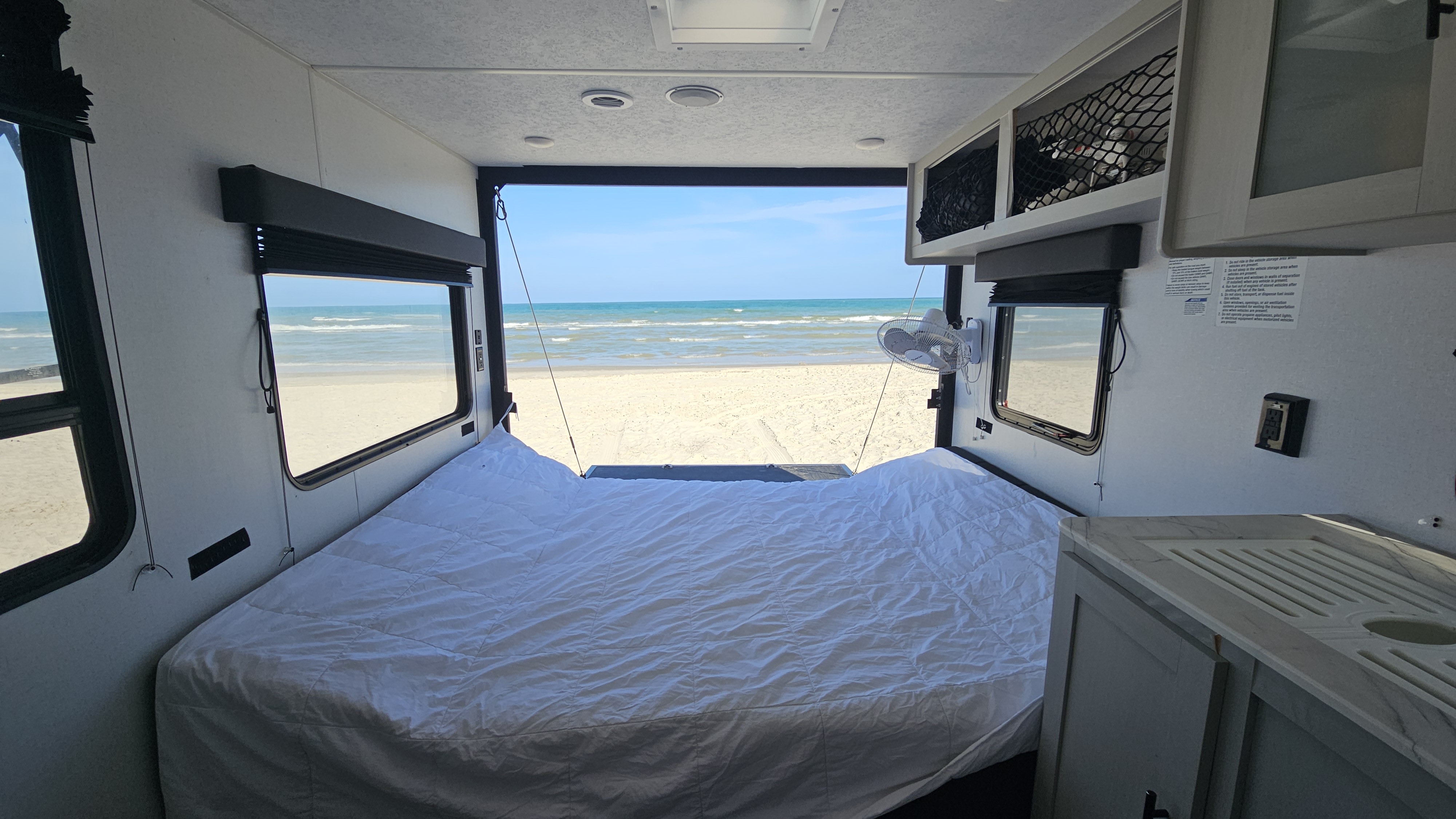 RV rental bedroom with a stunning beach view. Wake up to ocean sounds from your comfy mobile home on sandy shores.. Forest River Wildwood 2022