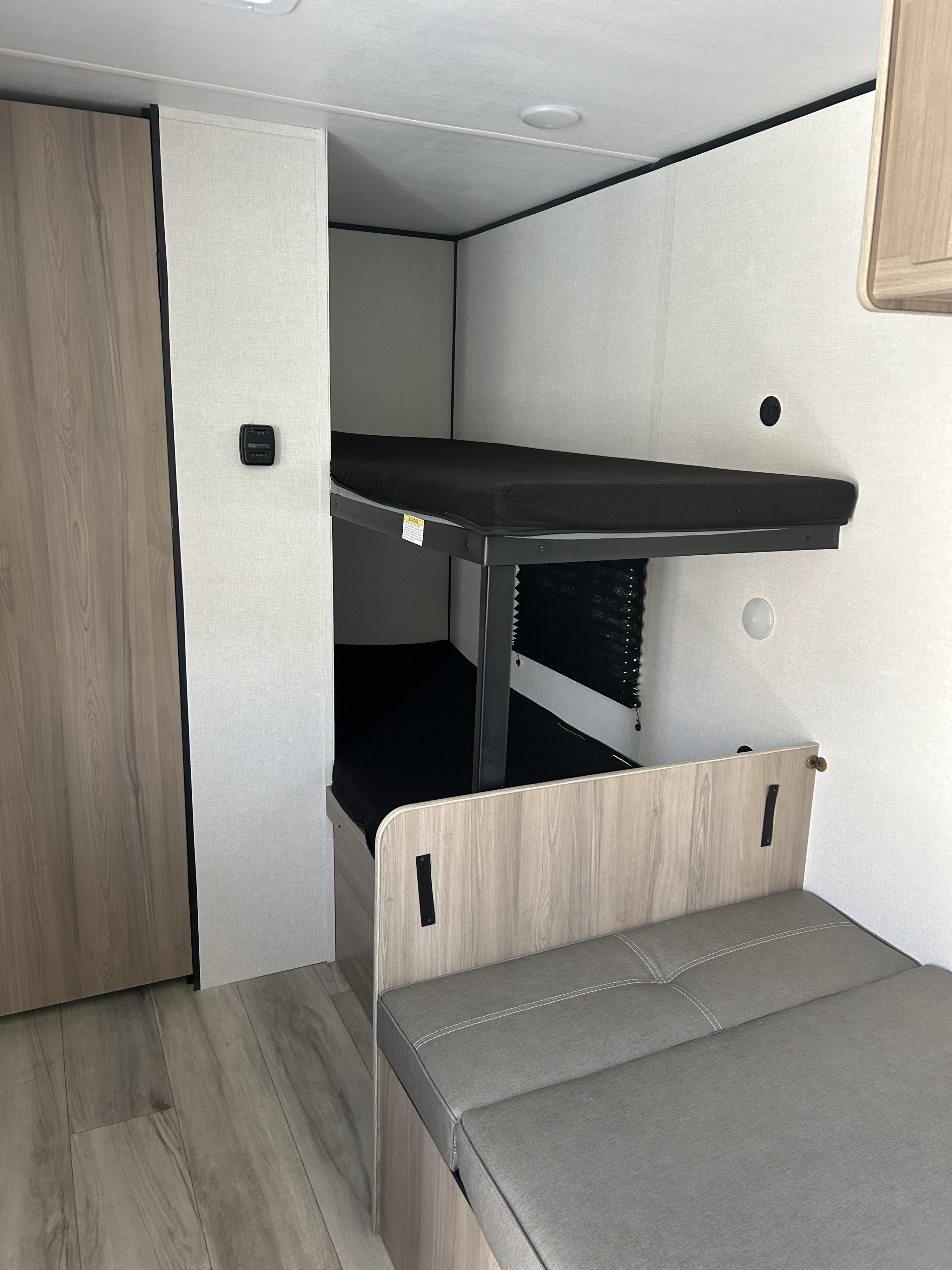 This RV rental shows a clean interior with bunk beds, a wood-look wardrobe, and gray dinette seating. Perfect for your travels.. Coleman Lantern 17B 2025