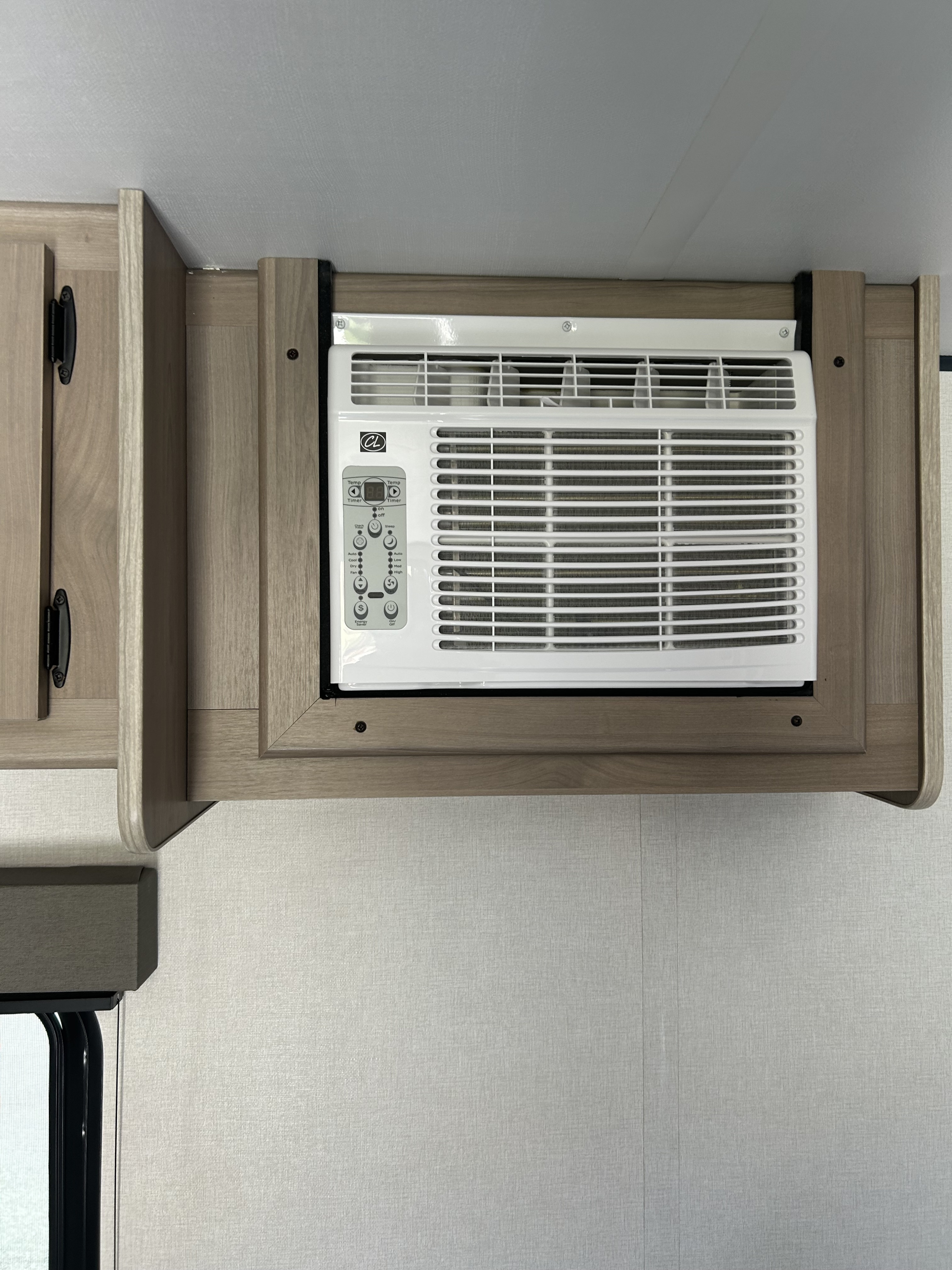 This RV rental cabin features a built-in air conditioning unit with digital controls, integrated into light wood cabinetry.. Coleman Lantern 17B 2025