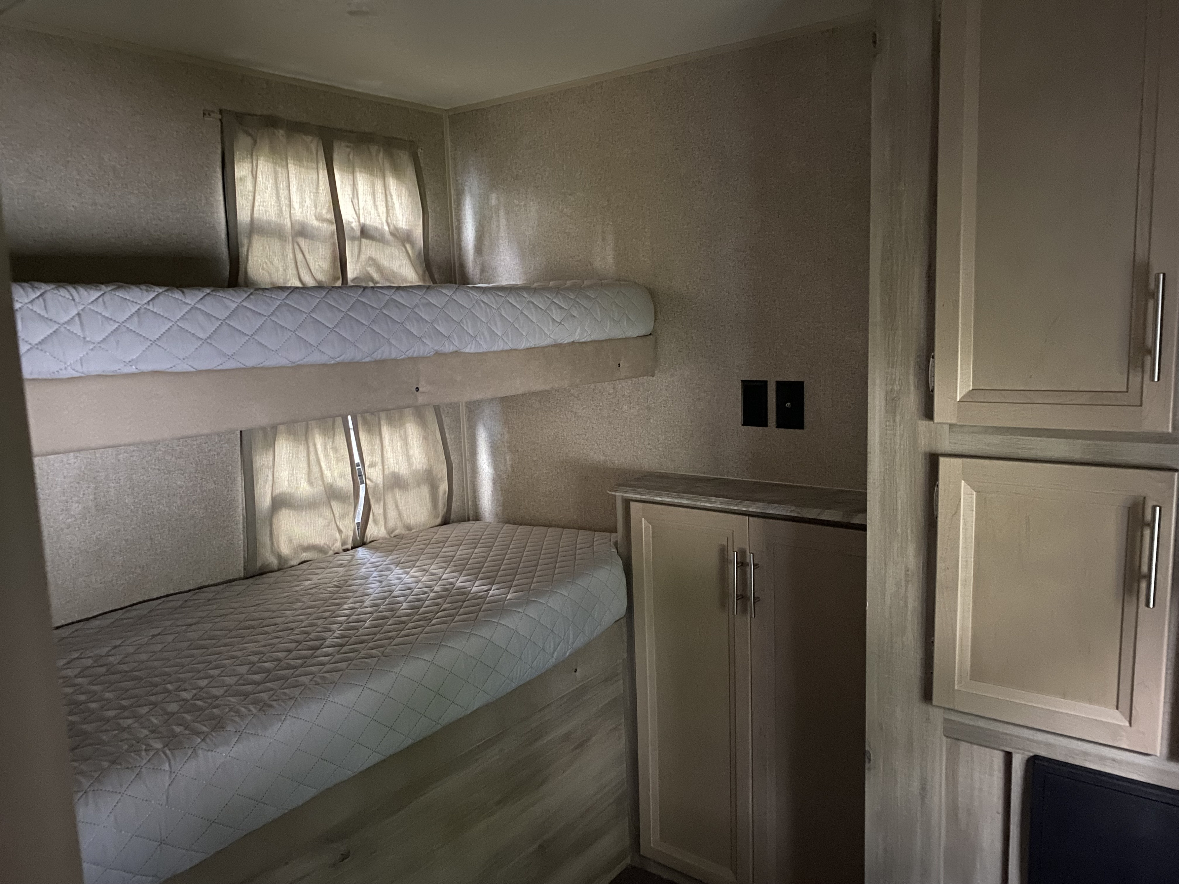 Compact RV rental interior featuring cozy bunk beds with quilted mattresses, windows, and built-in storage.. Forest River Coachmen Catalina Legacy 2019