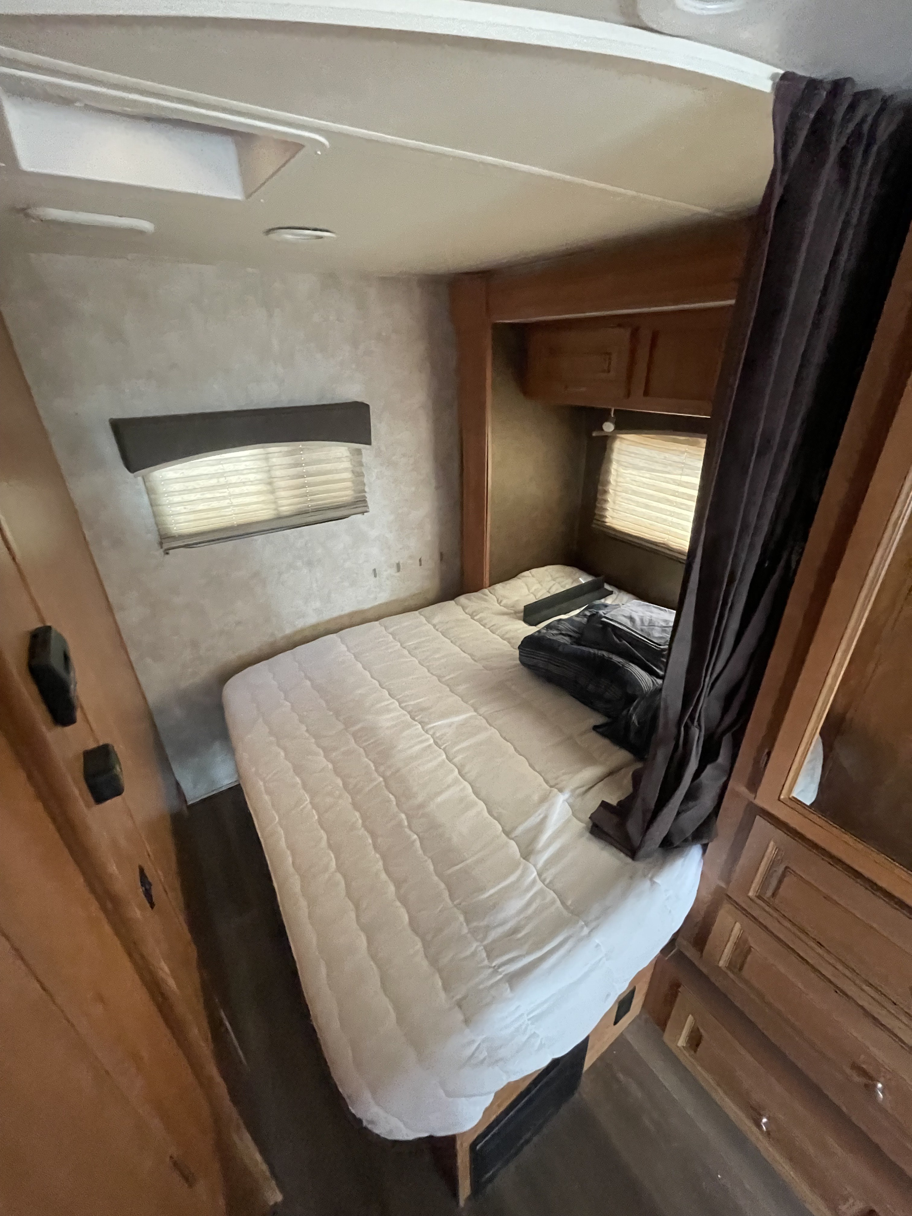 Cozy RV rental bedroom featuring a comfortable bed, window blinds, and built-in storage for travel comfort.. Nexus RV Phantom 2015