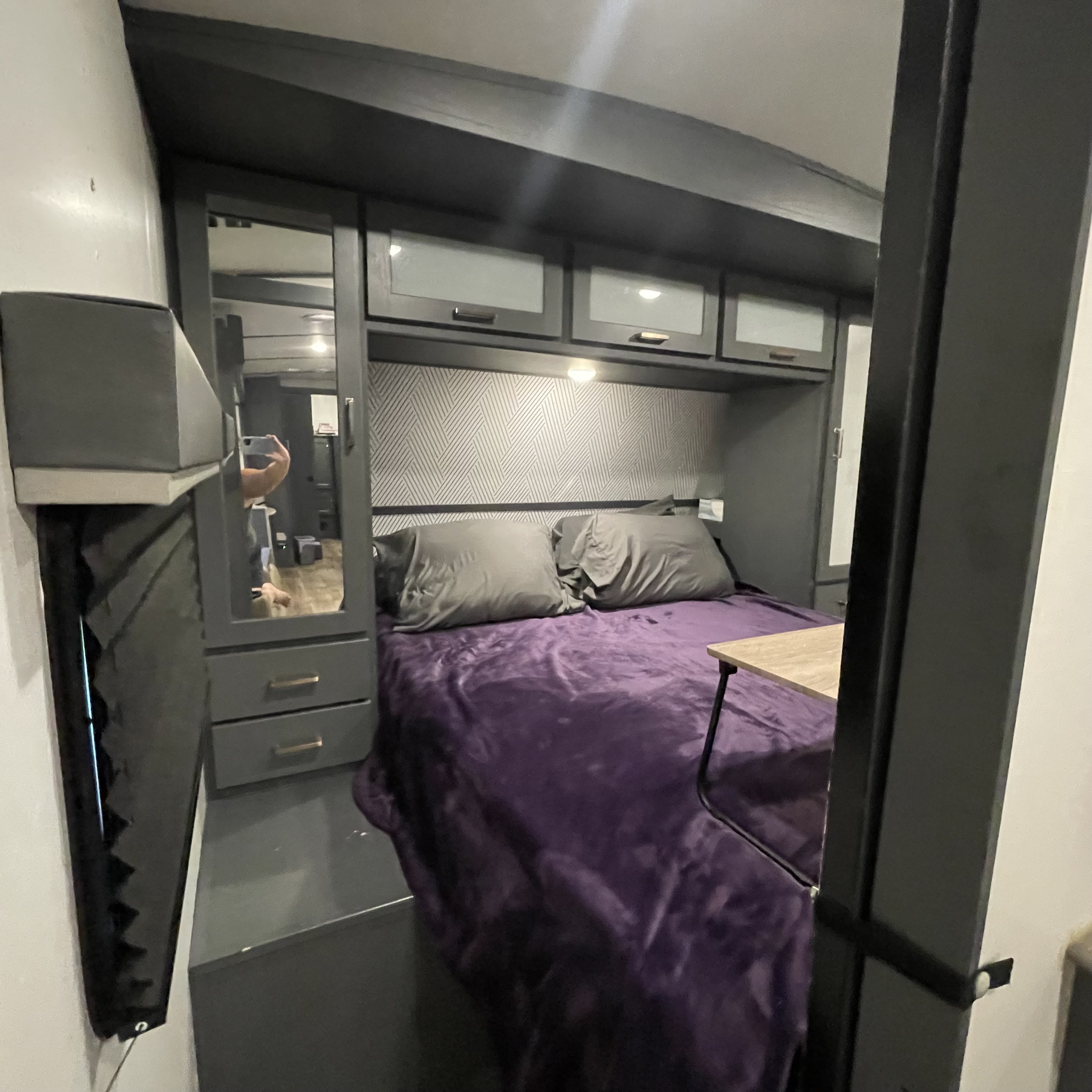 Experience comfort in this RV rental bedroom featuring a bed with purple blanket, mirrored closet, and overhead storage.. Keystone RV Bullet Ultra Lite 2022