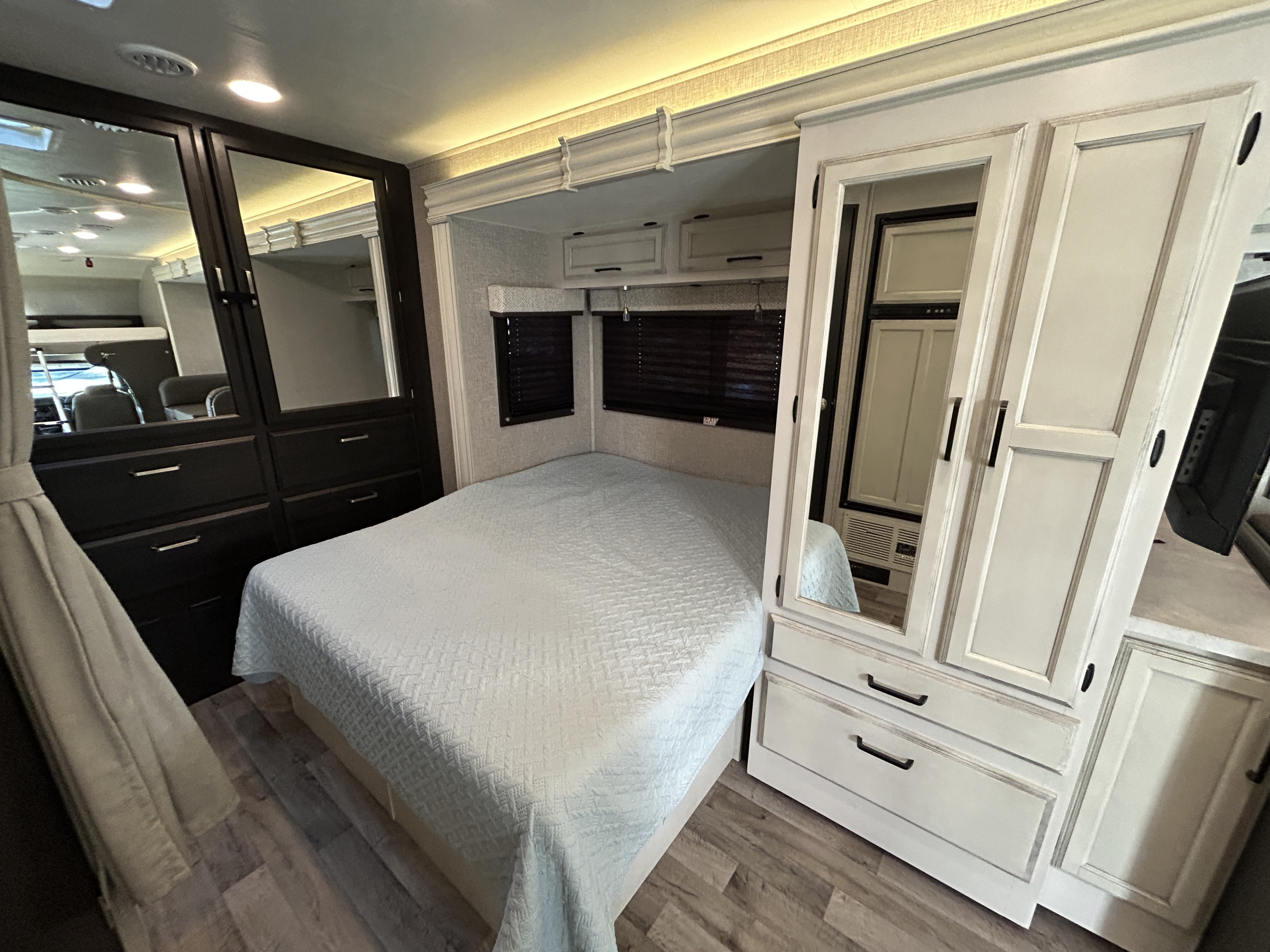 Cozy RV rental bedroom features a queen bed, mirrored wardrobes, and window blinds, all on wood-look flooring.. Jayco redhawk 2023
