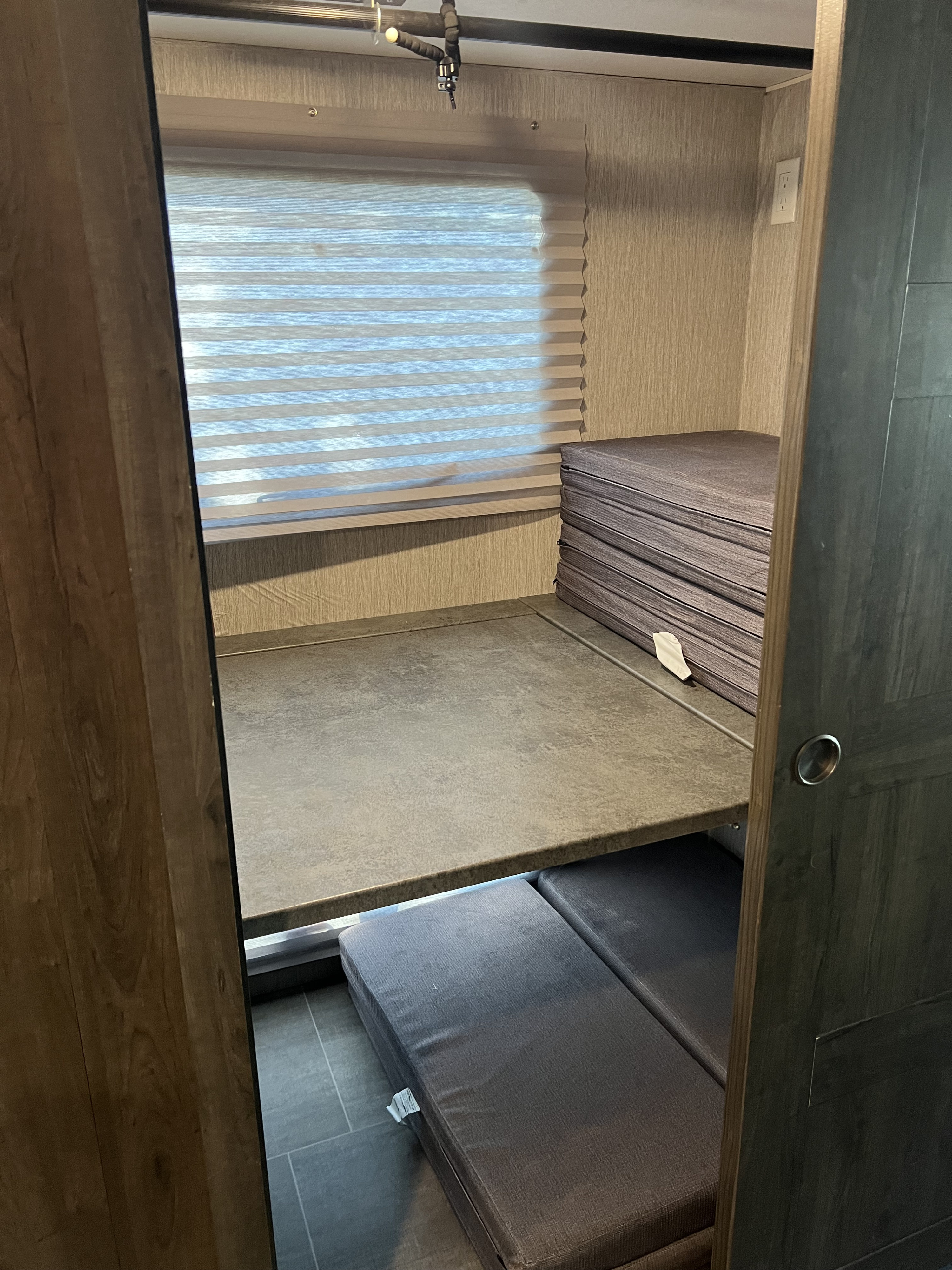 RV rental bunk bed setup with upper platform, window, and lower cushions for comfortable sleeping.. Coachmen Mirada 2021
