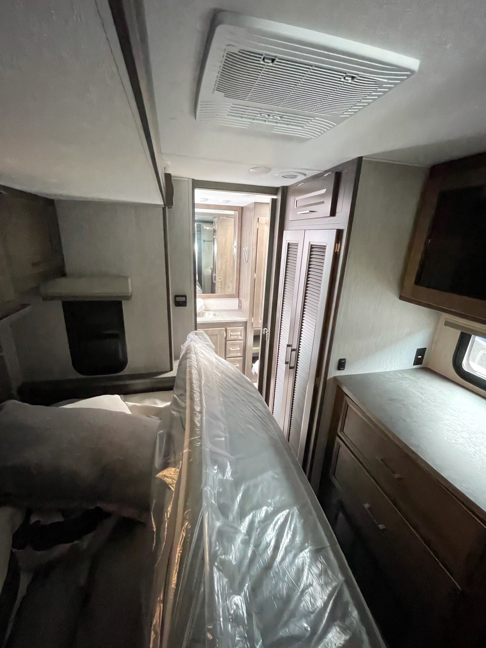 Clean RV rental interior: bedroom features a new, plastic-wrapped mattress, ceiling AC, and bathroom access.. Coachmen Mirada 2021
