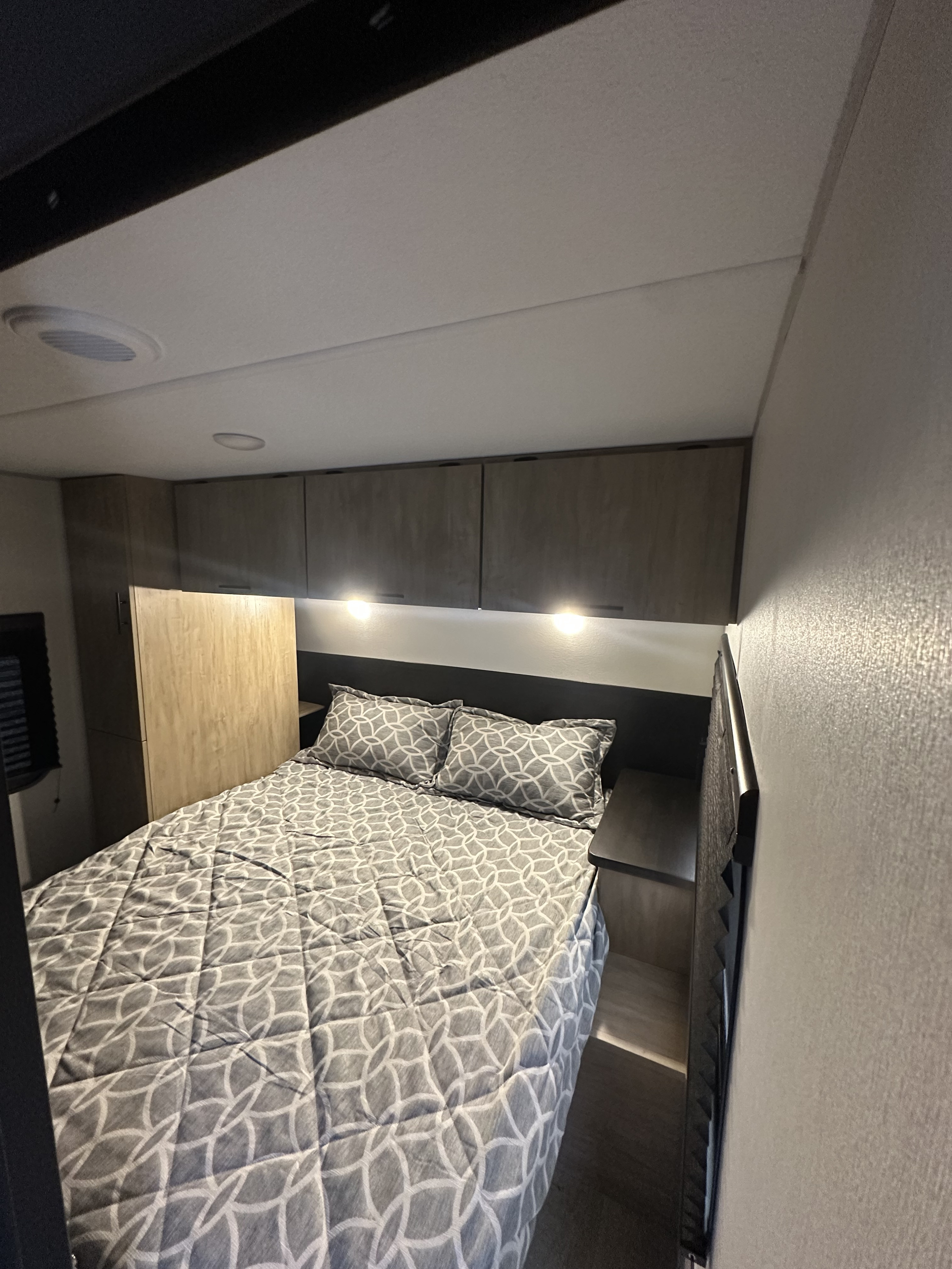 Explore a comfy RV rental travel trailer bedroom with a patterned bed, storage cabinets, and ambient lighting.. Forest River Cherokee Grey Wolf 2026