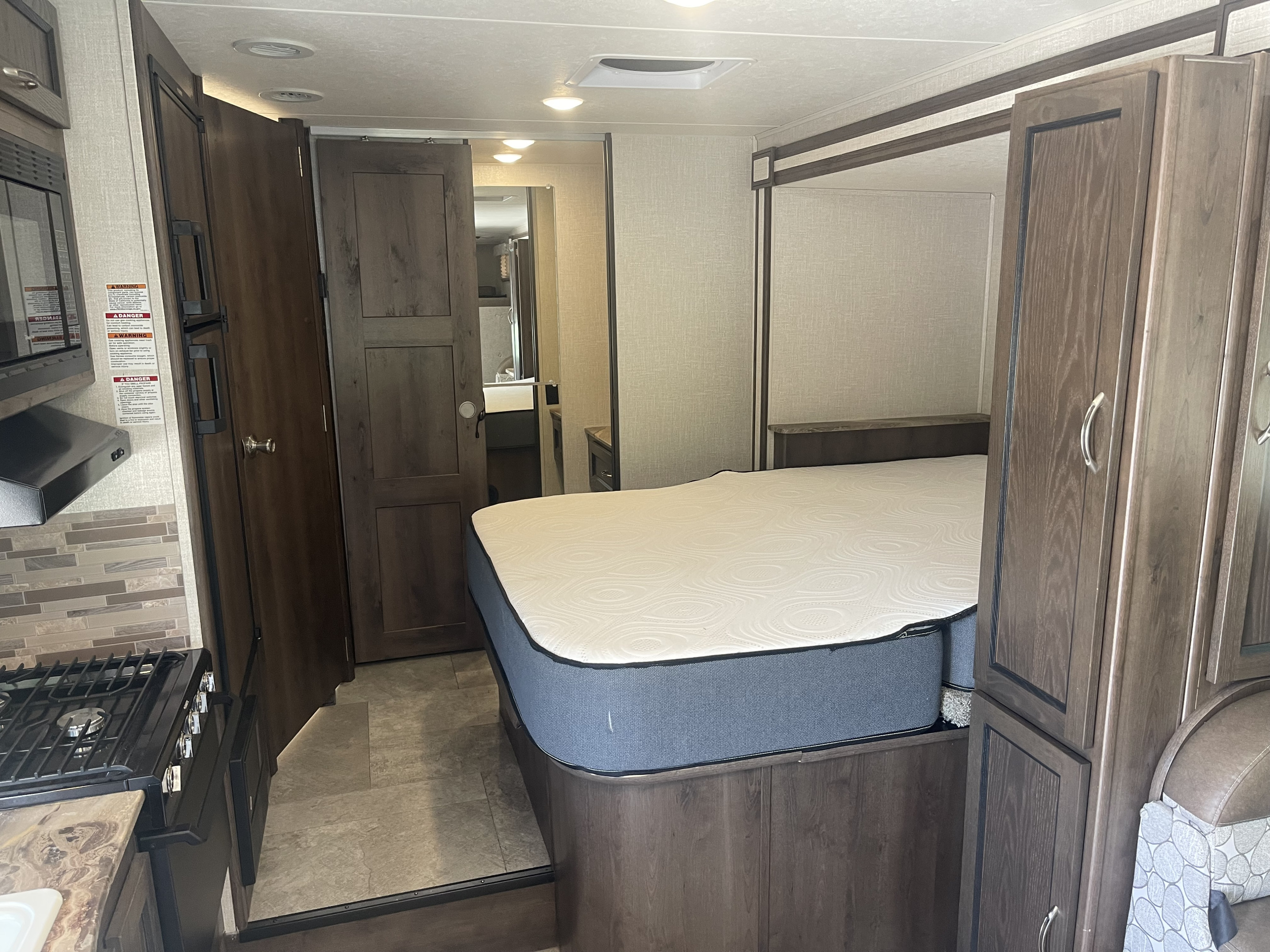 Inside a comfortable RV rental: master bedroom, full kitchen with stove and microwave, plus bathroom access. Ready for your next trip!. Forest River Coachmen Freelander 2018
