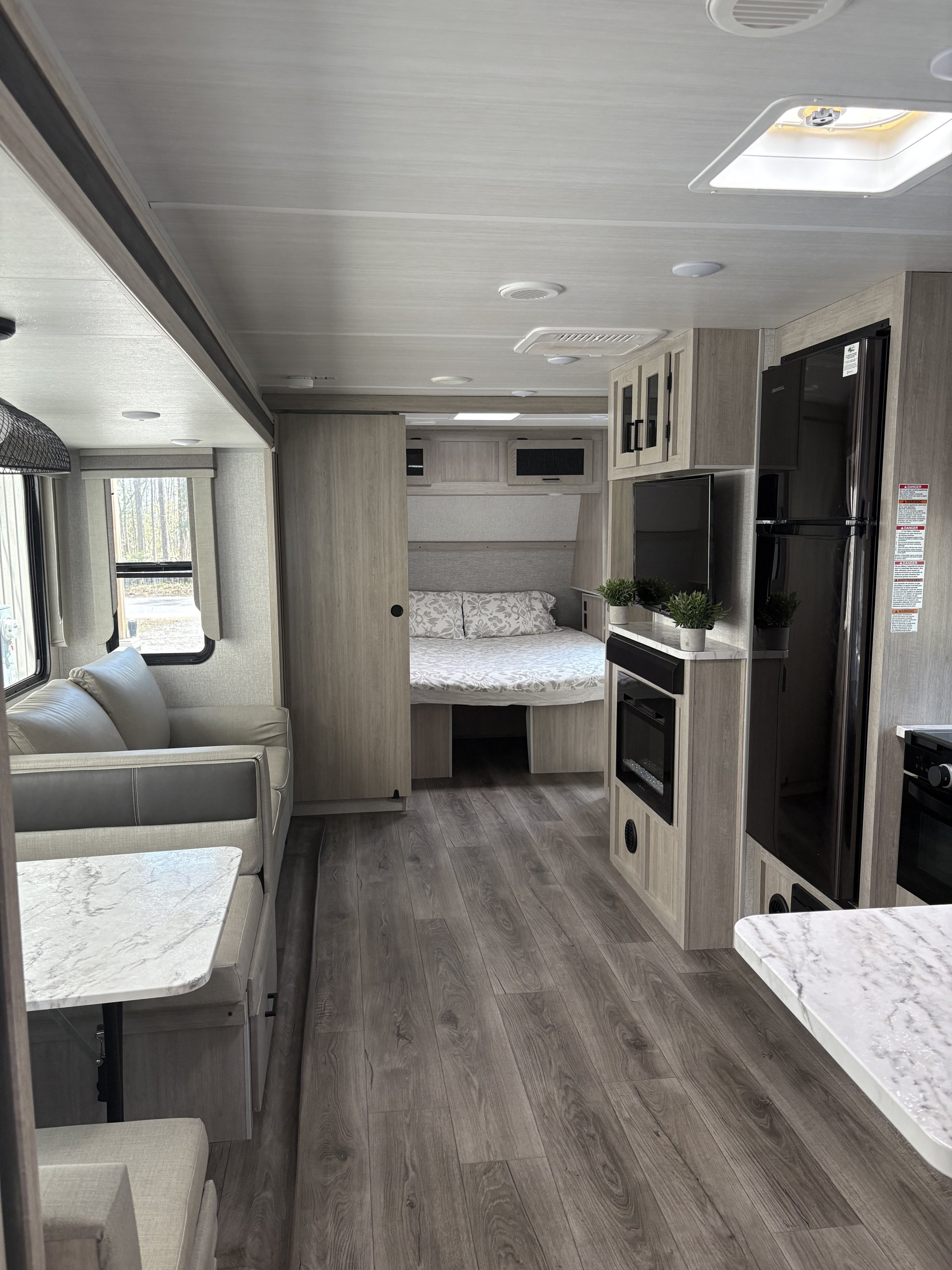 Spacious, bright RV rental interior with light wood tones, featuring a living area, kitchen, and back bedroom.. East to West Alta 2022