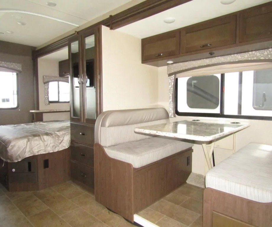 RV rental interior showcasing a comfortable bedroom, central wardrobe, and a bright dinette with table.. Thor Chateau 2019