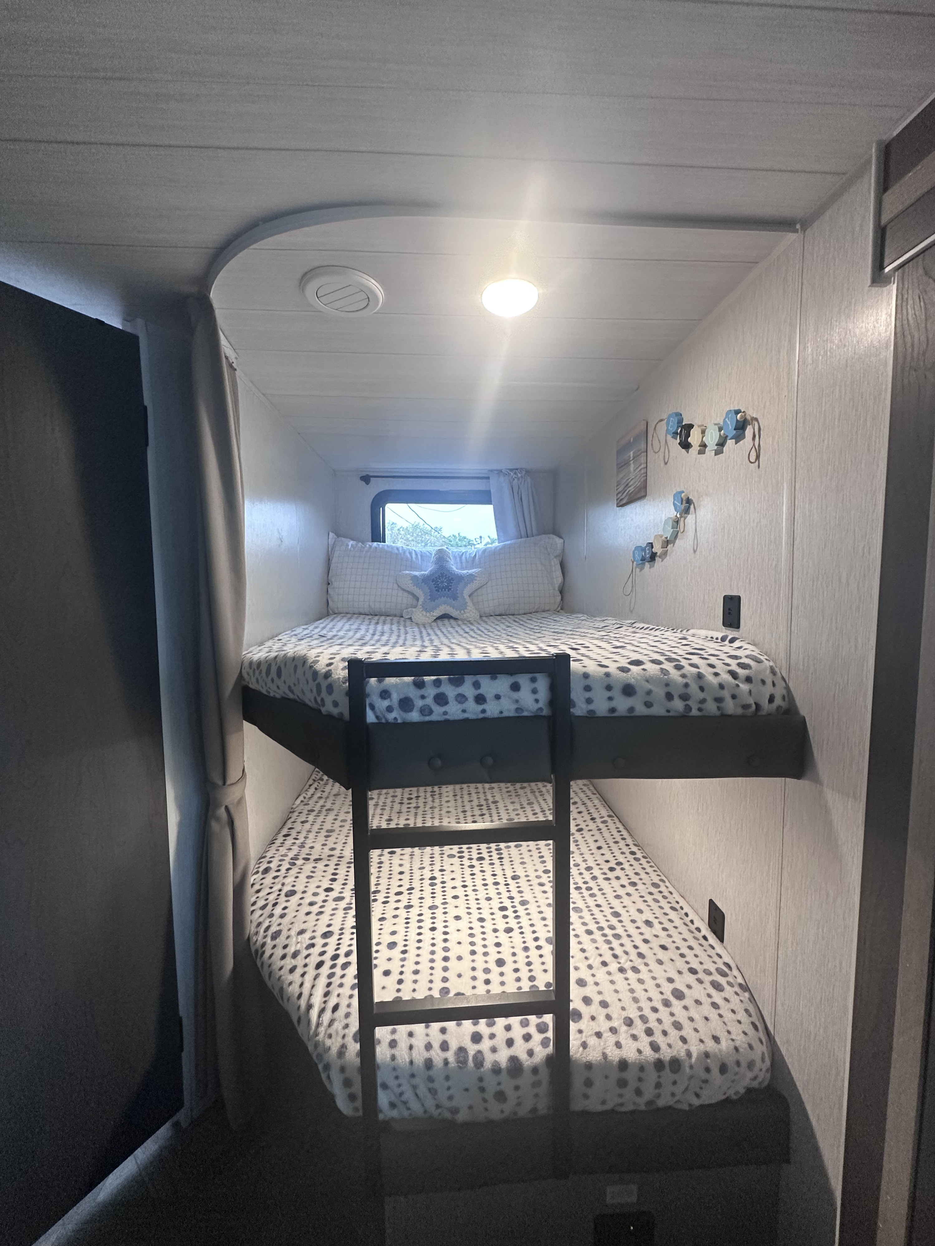 Cozy bunk beds inside an RV rental, featuring blue dot bedding and a window, ideal for extra sleeping space.. Forest River Salem Cruise Lite Platinum 2023