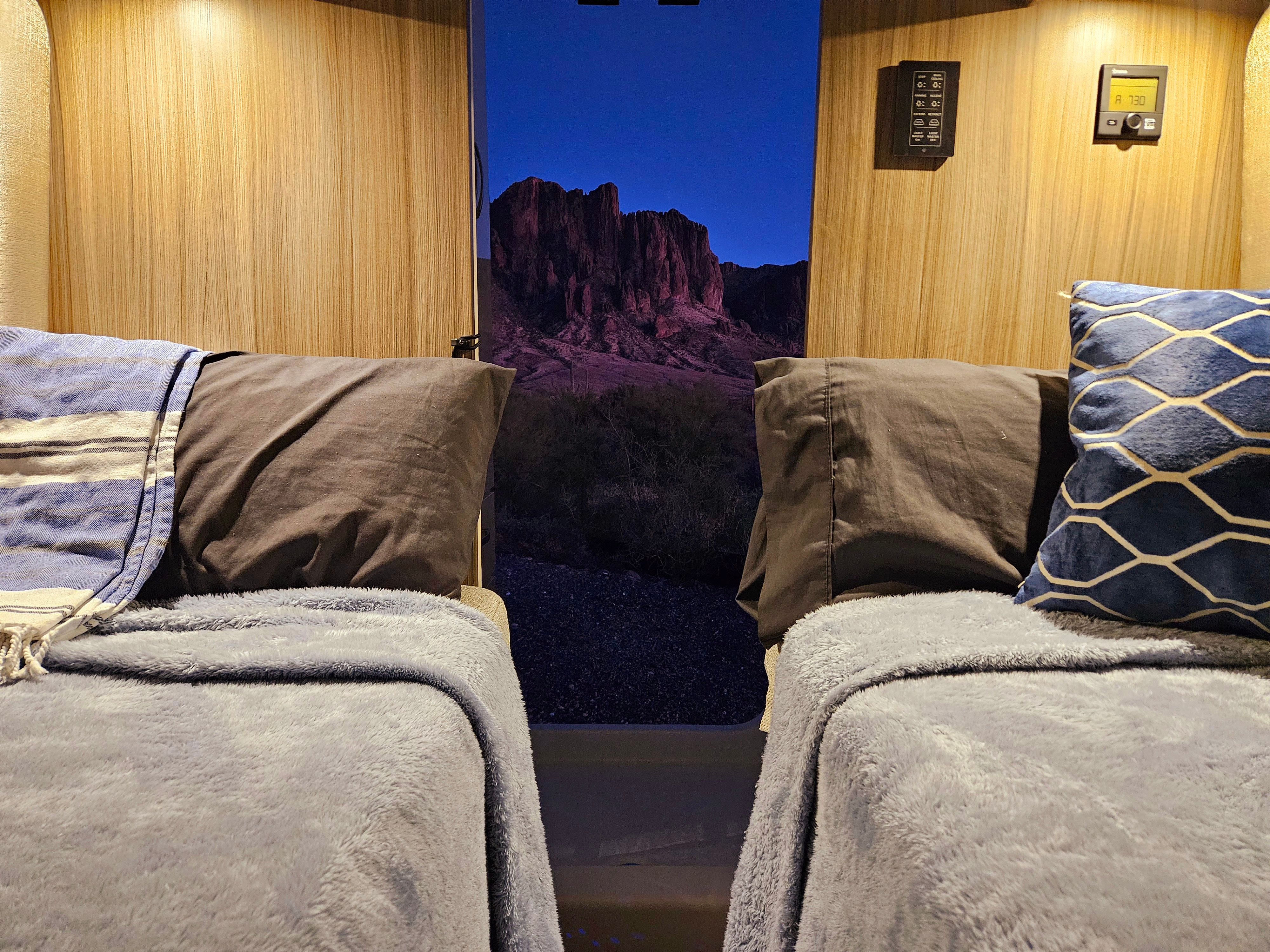 Cozy RV rental interior with two beds facing a stunning twilight mountain view, perfect for comfortable travels.. RAM Entegra Ethos 20T 2024