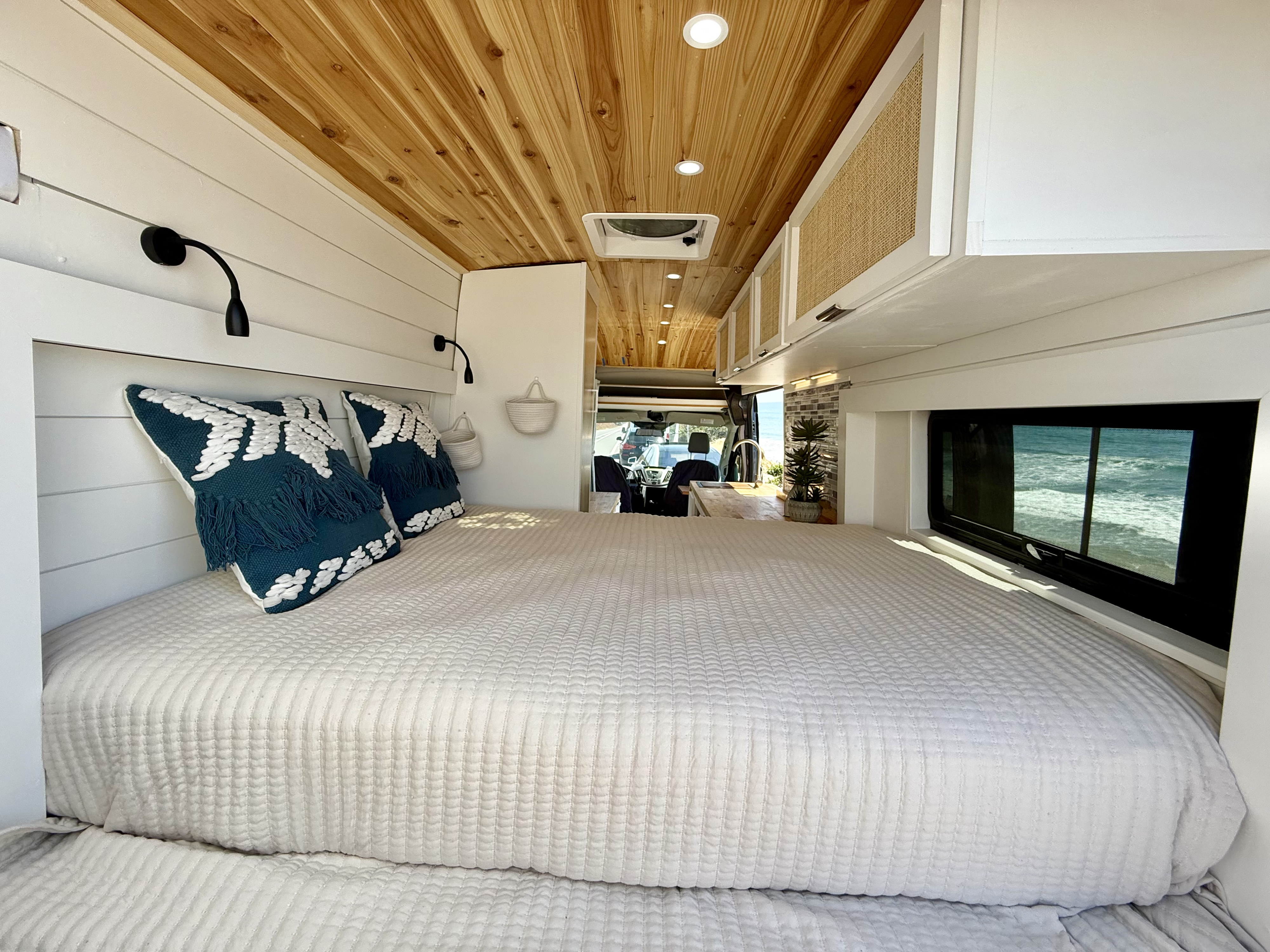 Experience van life in this cozy RV rental! Features a comfy bed, wood ceiling, white walls, and a beautiful ocean view.. Ford Transit 250 Cargo High Roof Extended 2019