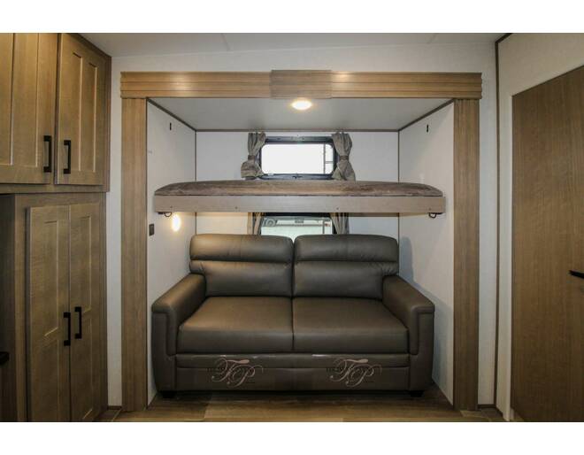 Explore this RV rental's versatile interior: a wooden top bunk rests over a comfortable pull-out sofa bed, amidst warm cabinetry.. K-Z Durango 2024