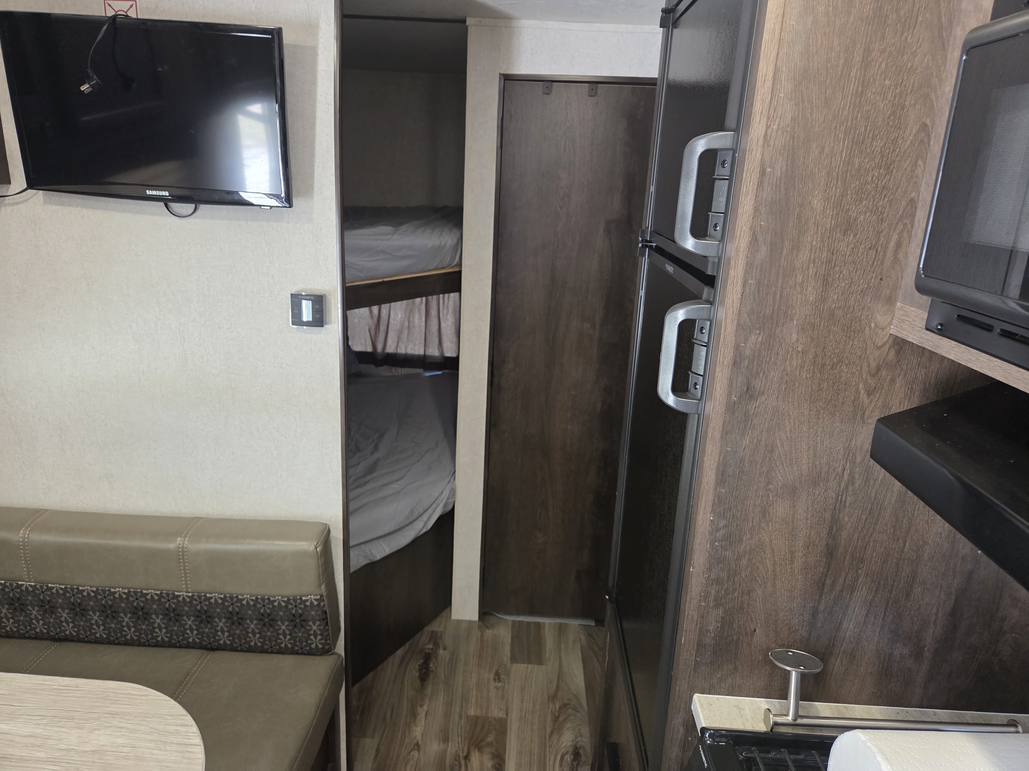 Spacious RV rental interior, featuring a dinette with TV, bunk beds, and a full kitchen area with refrigerator and microwave.. Starcraft Autumn Ridge Outfitter 2019