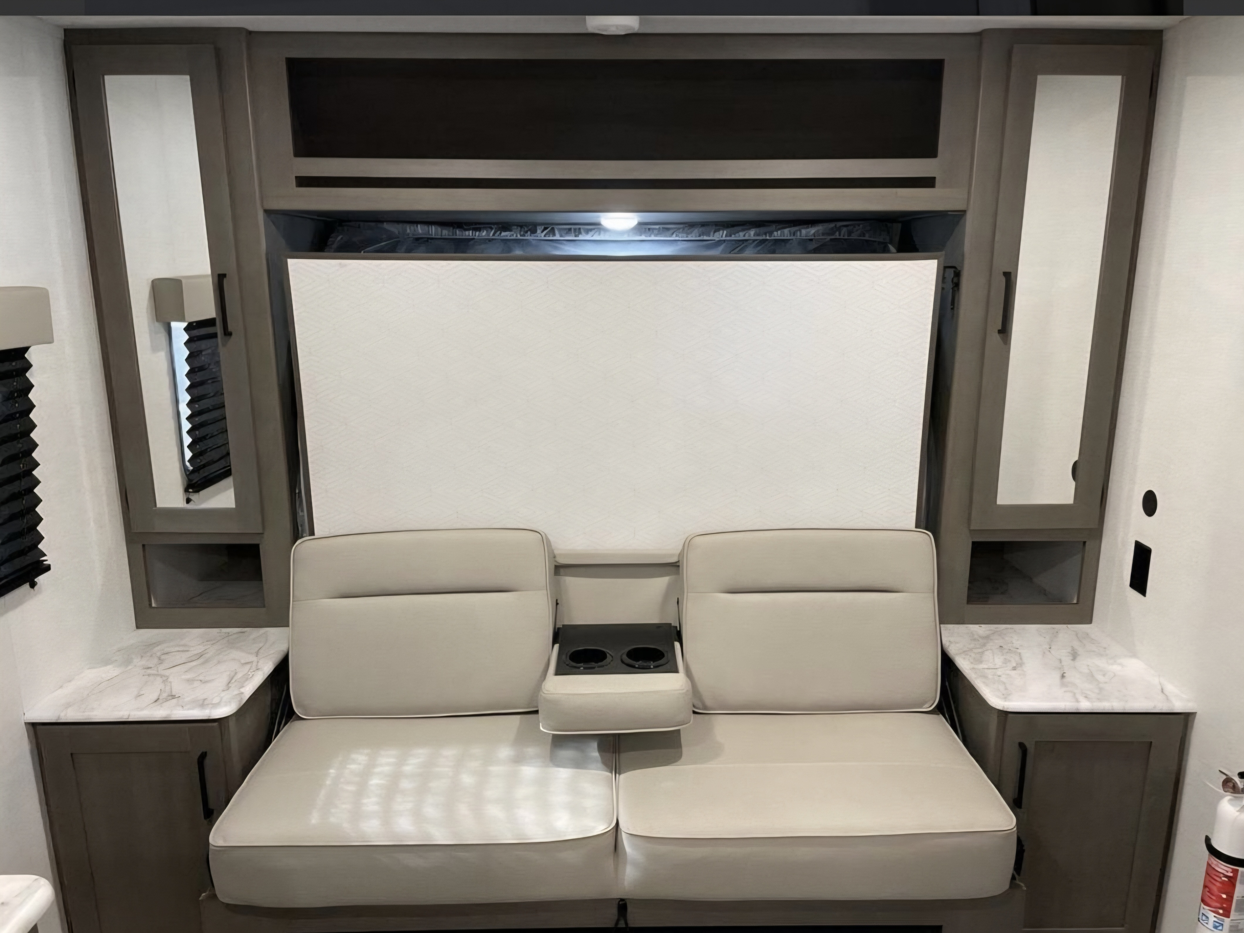 RV rental interior: light-toned seating, folding Murphy bed, storage, and side countertops. Ideal for compact living.. Grand design transcend one 151rb 2025