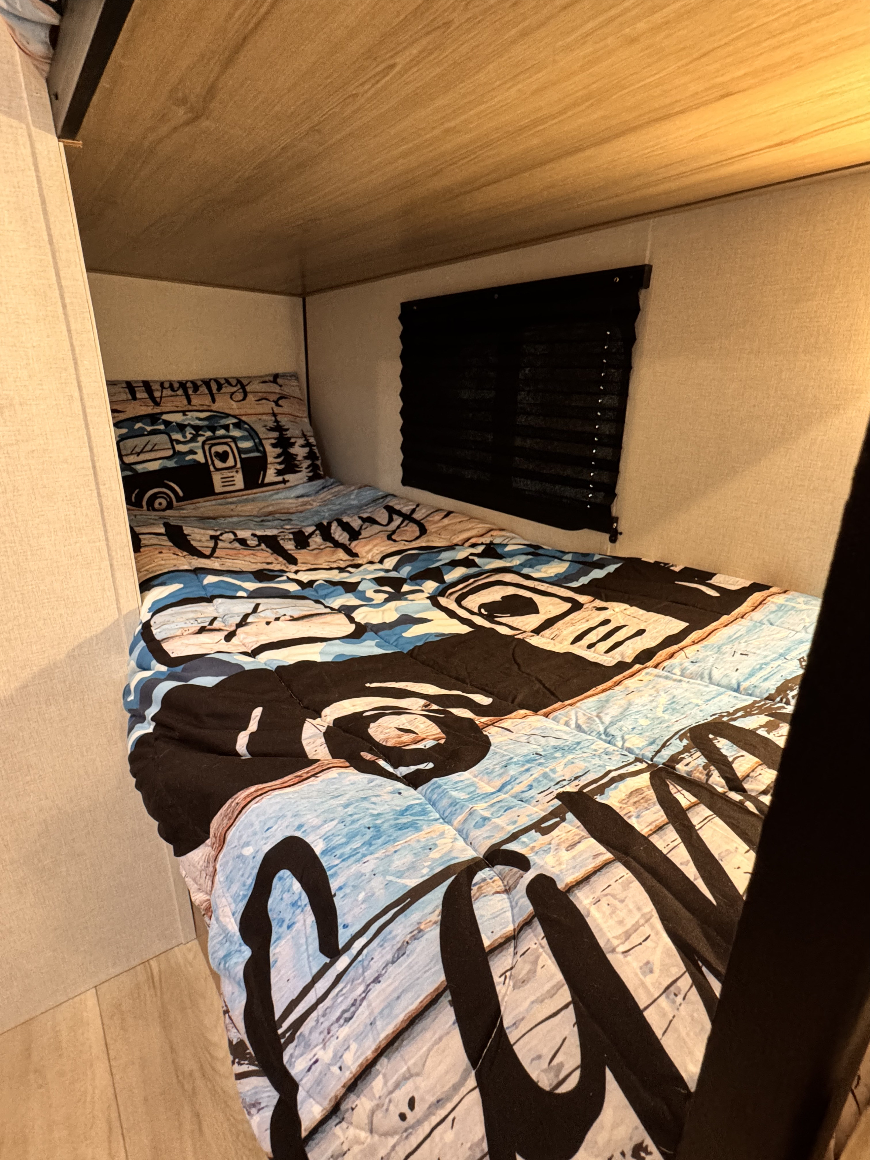Cozy RV rental bunk bed with camping-themed bedding. Features a window with blinds, perfect for a relaxing trip.. Keystone Coleman 17B 2025