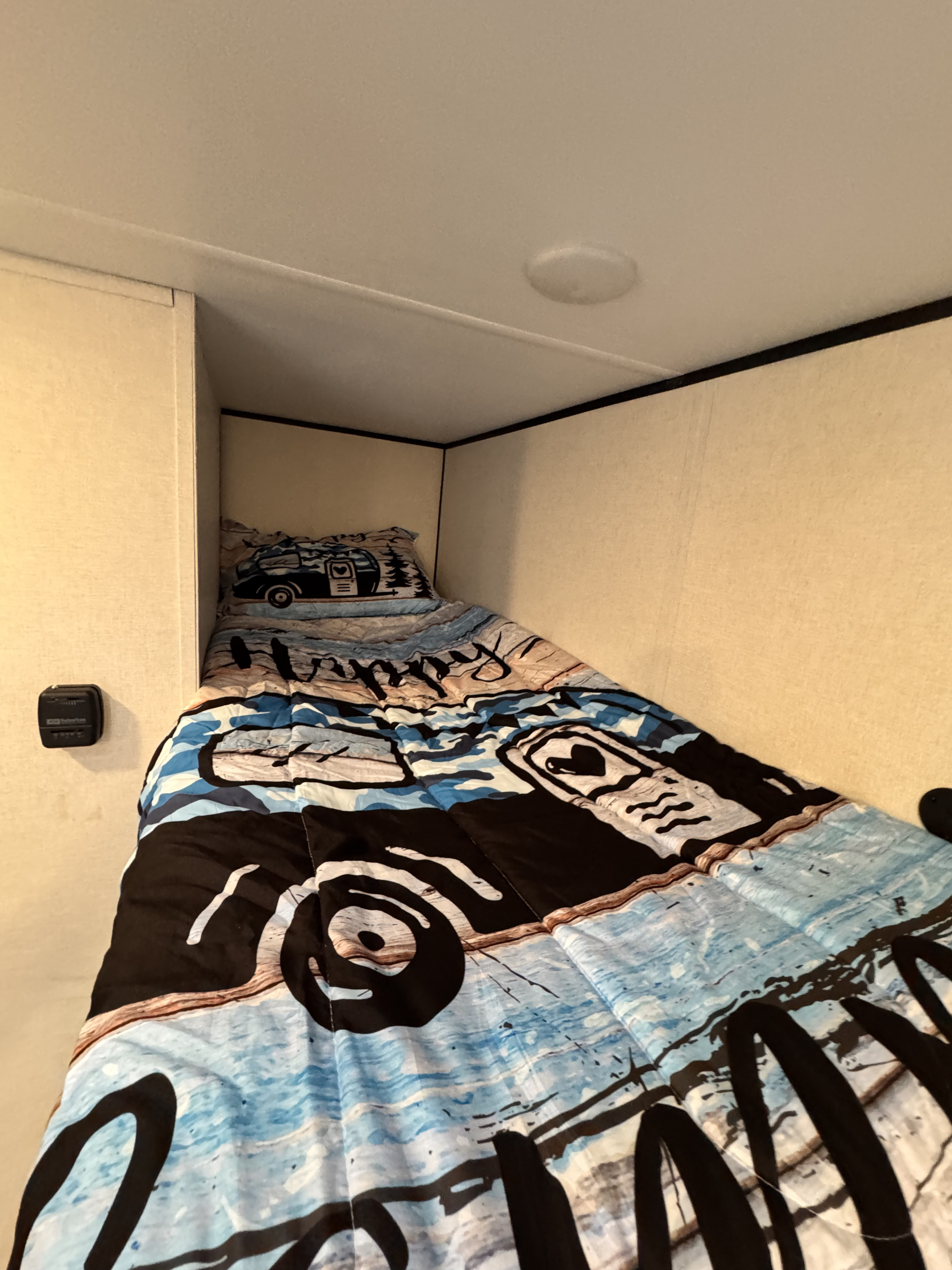 RV rental: Cozy bunk bed with blue camper bedding, a ceiling light, and wall-mounted thermostat.. Keystone Coleman 17B 2025
