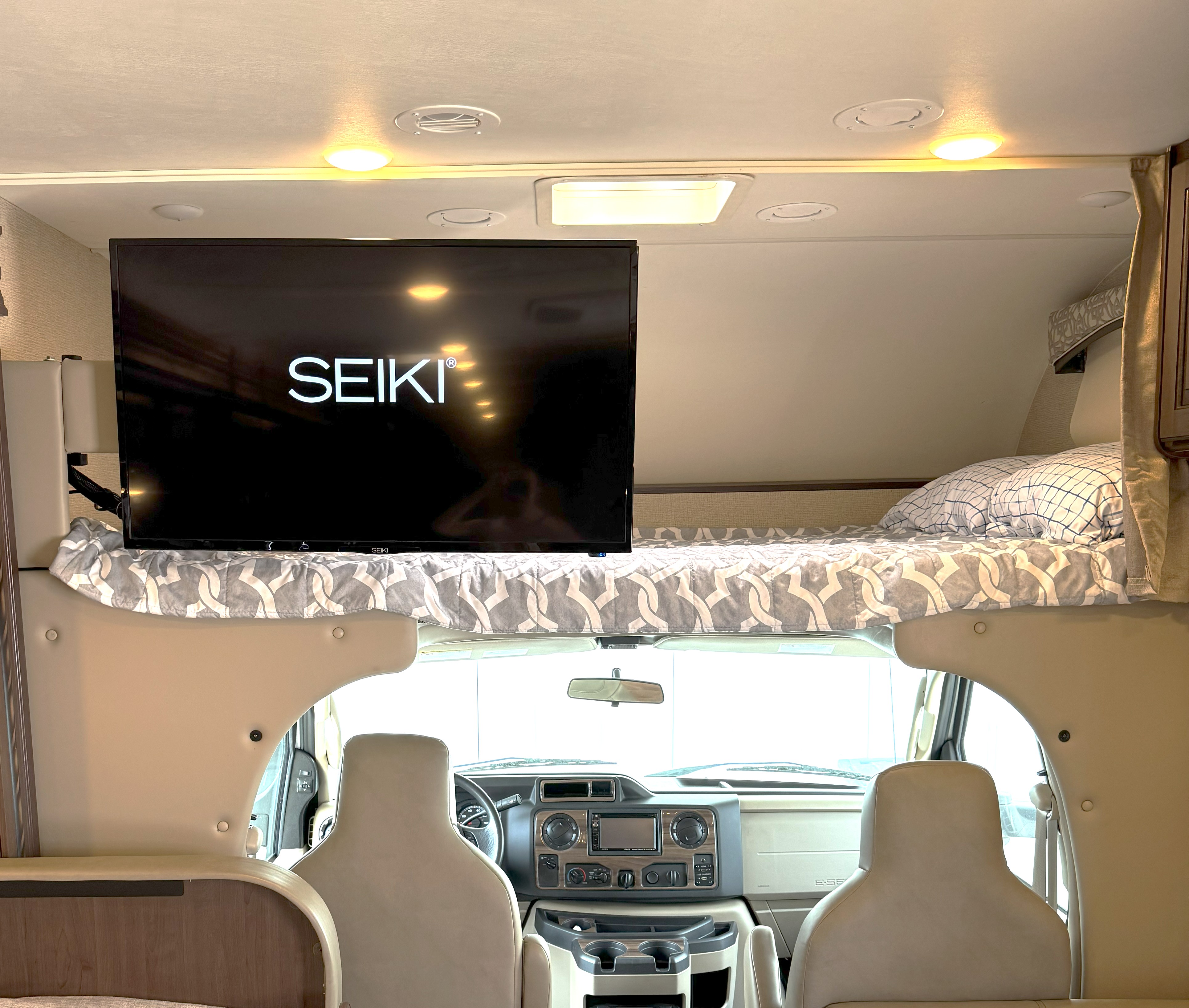 Spacious RV rental interior with a comfy overhead bunk bed and TV above the driver's cab.. Thor Chateau 2017