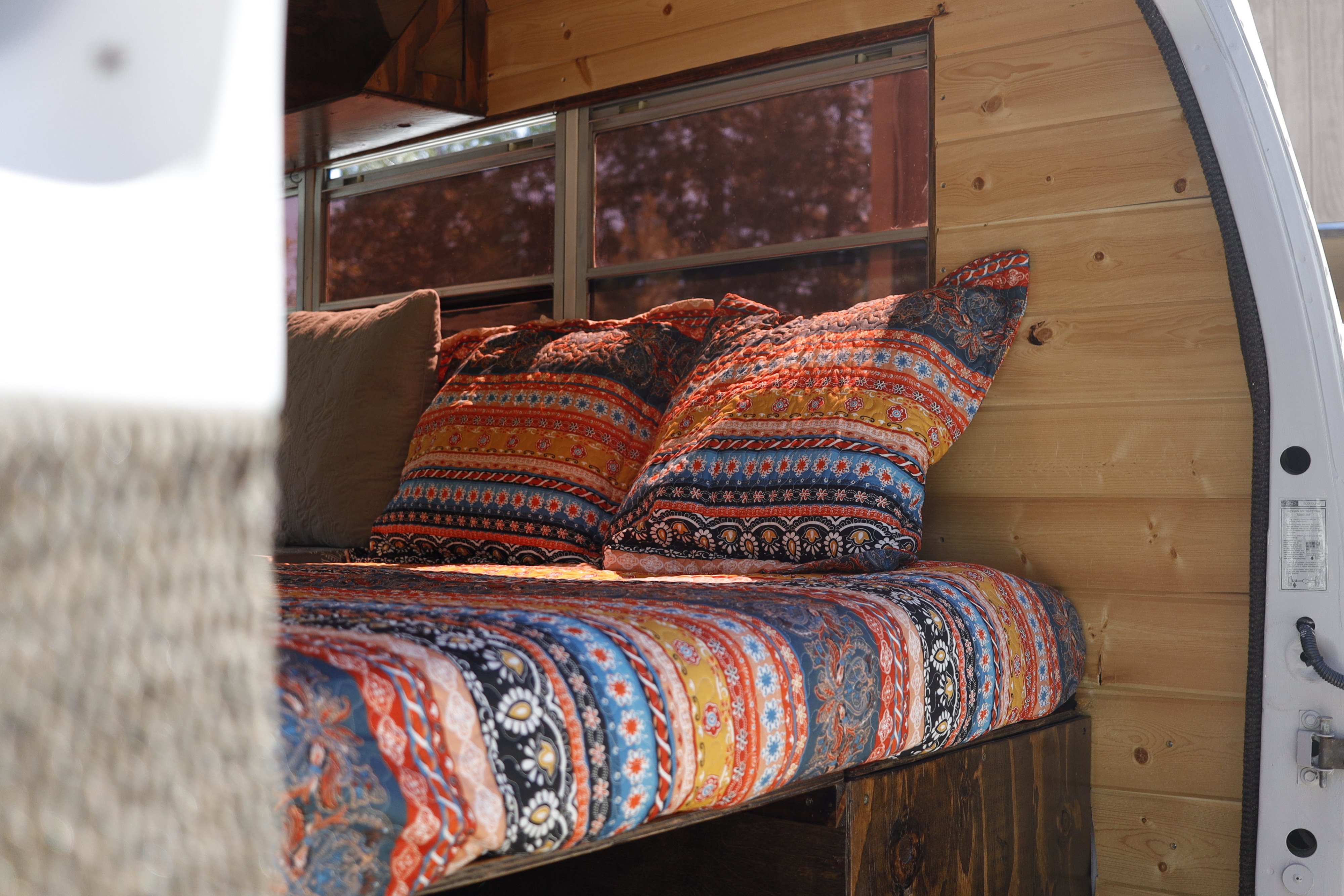 Enjoy a cozy rv rental! This custom van interior features a vibrant patterned bed, wooden walls, and tinted windows.. Ford Econoline 1989