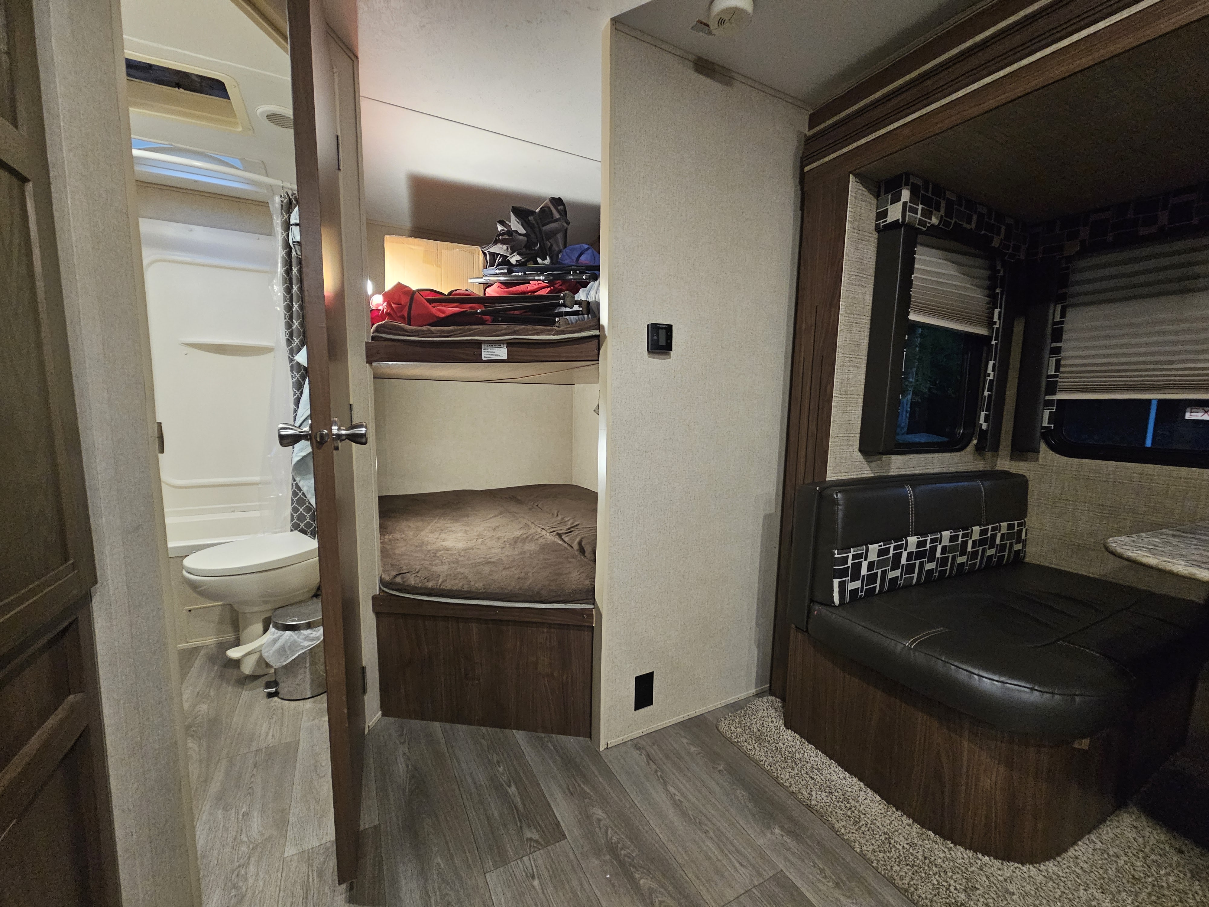 Inside an RV rental: view shows a bright bathroom, bunk beds with storage, and a comfortable dinette area.. Dutchmen Coleman Light 2018