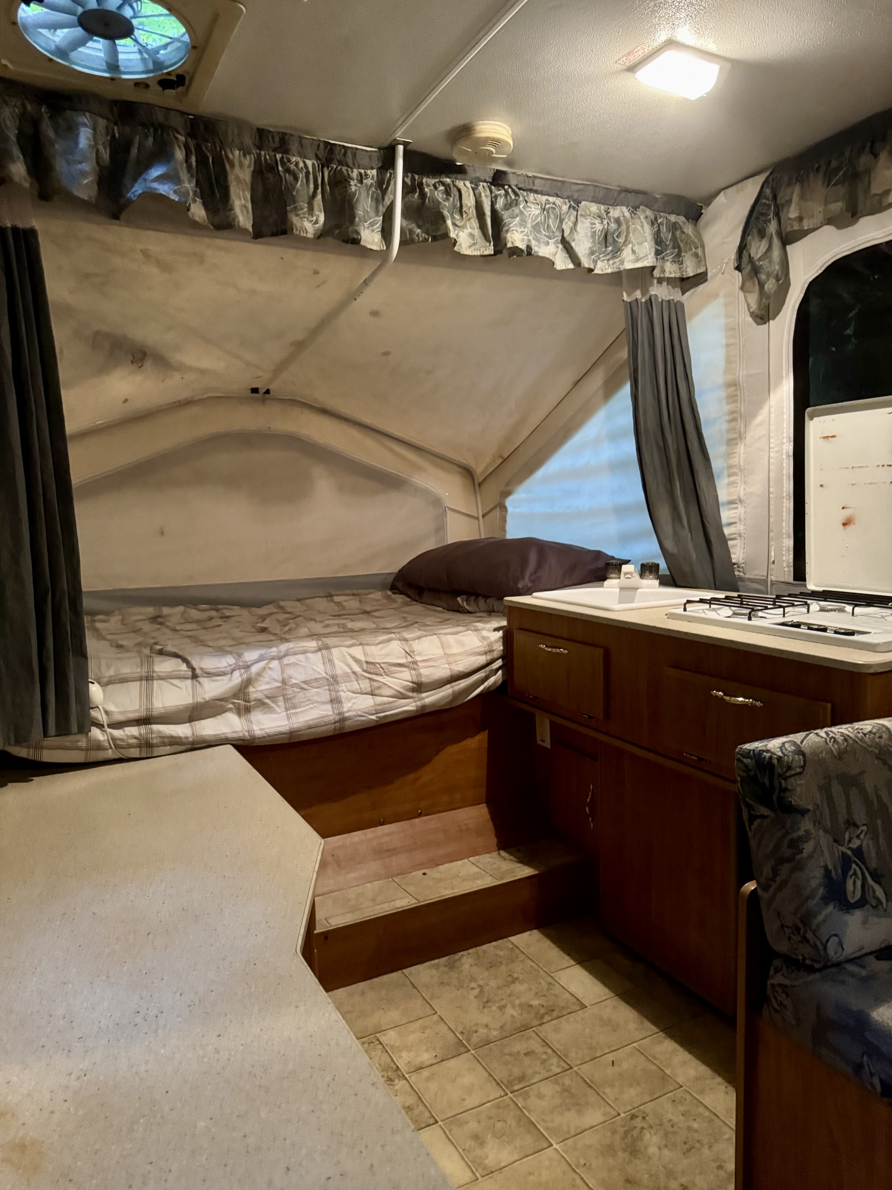 Experience this RV rental interior, featuring a pop-up bed area, compact kitchen, and dinette with vinyl flooring.. Forest River Flagstaff Off Road 2006