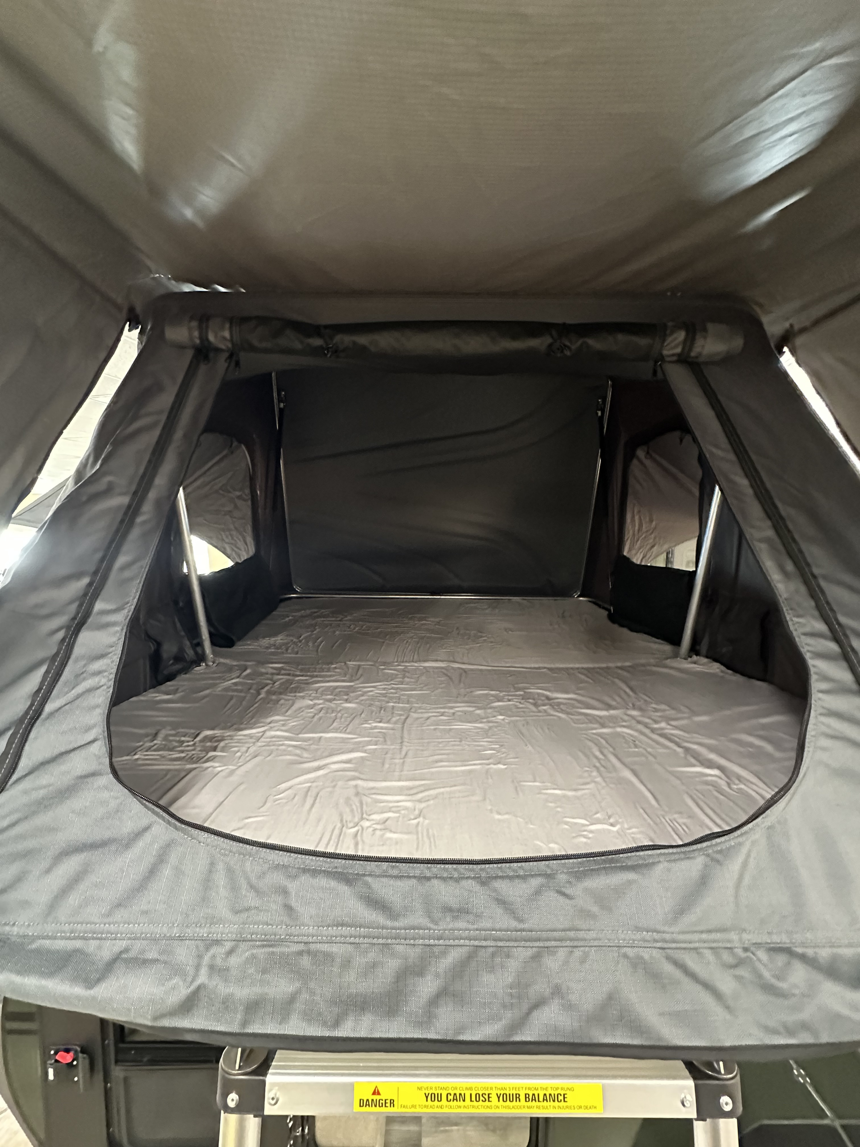 Inside a cozy **RV rental**'s rooftop tent, showing the comfy mattress & sleeping area. Perfect for **camping adventures**.. ModernBuggyRV 12LKR 2026