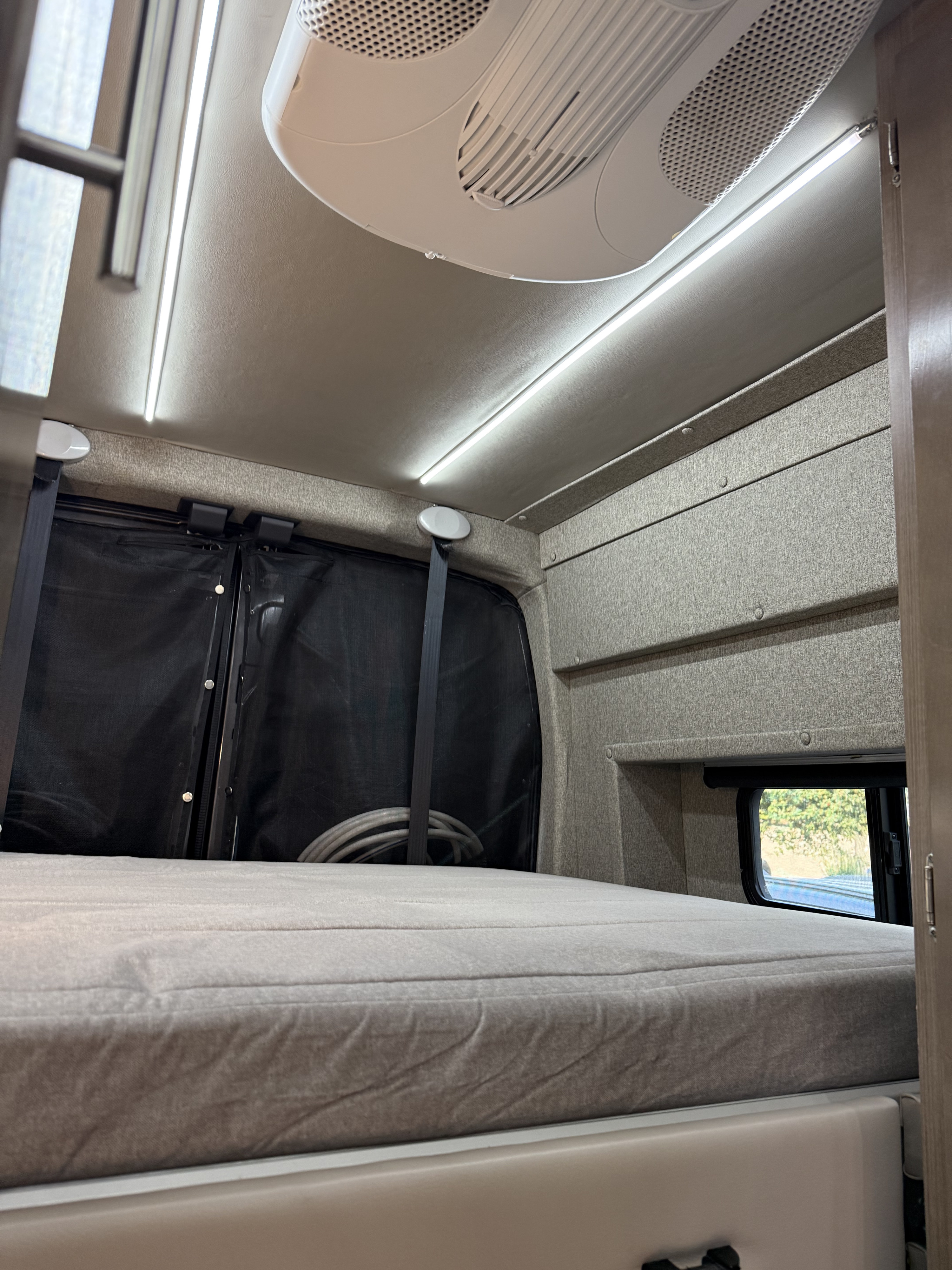 RV rental interior: cozy bed, overhead AC unit, bright LED lighting, and window screens for comfort.. Adventurer Ford TRIBUTE 2021